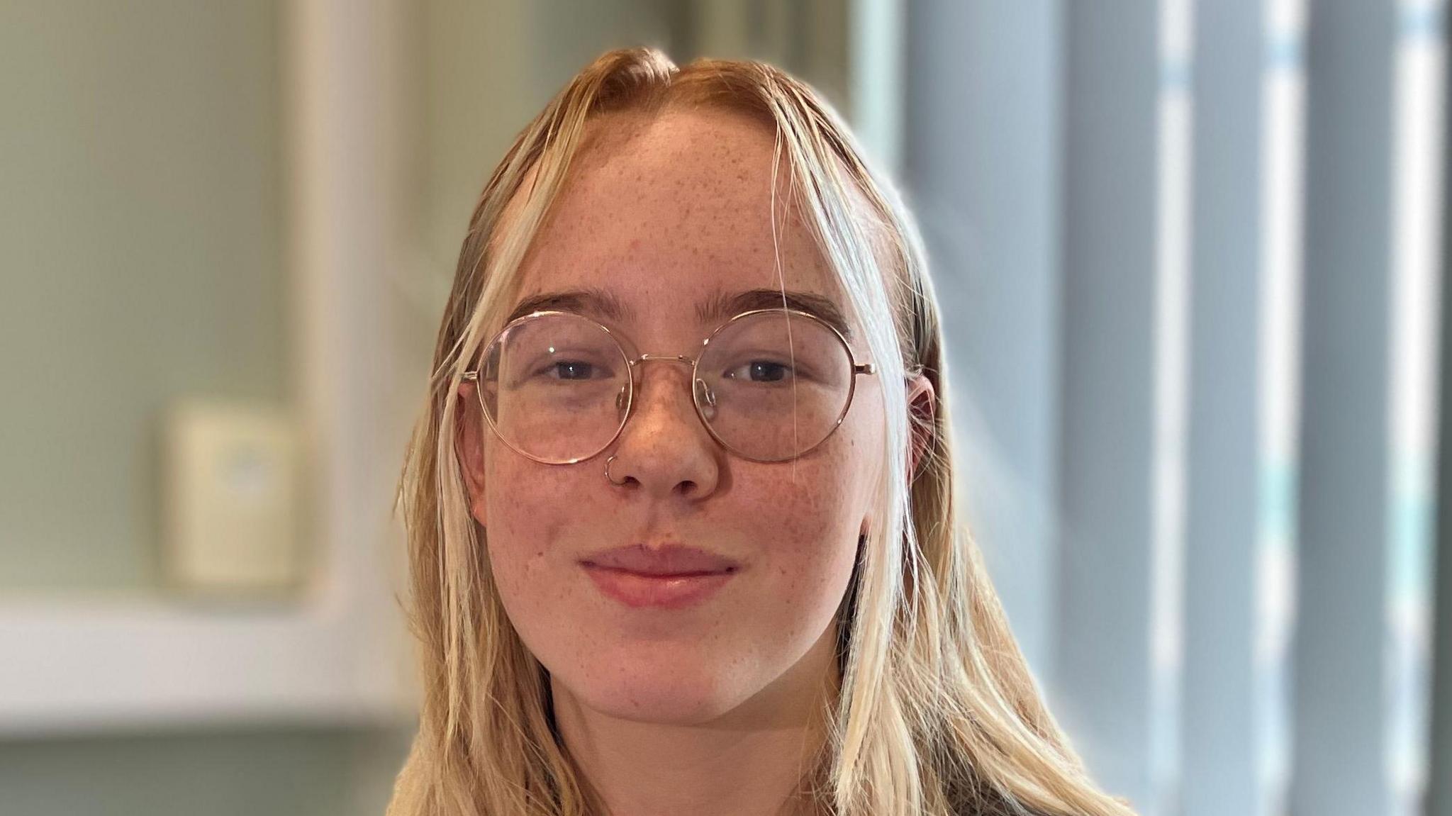 Lois Jones, who has long blonde hair and wire-framed glasses, smiling at camera