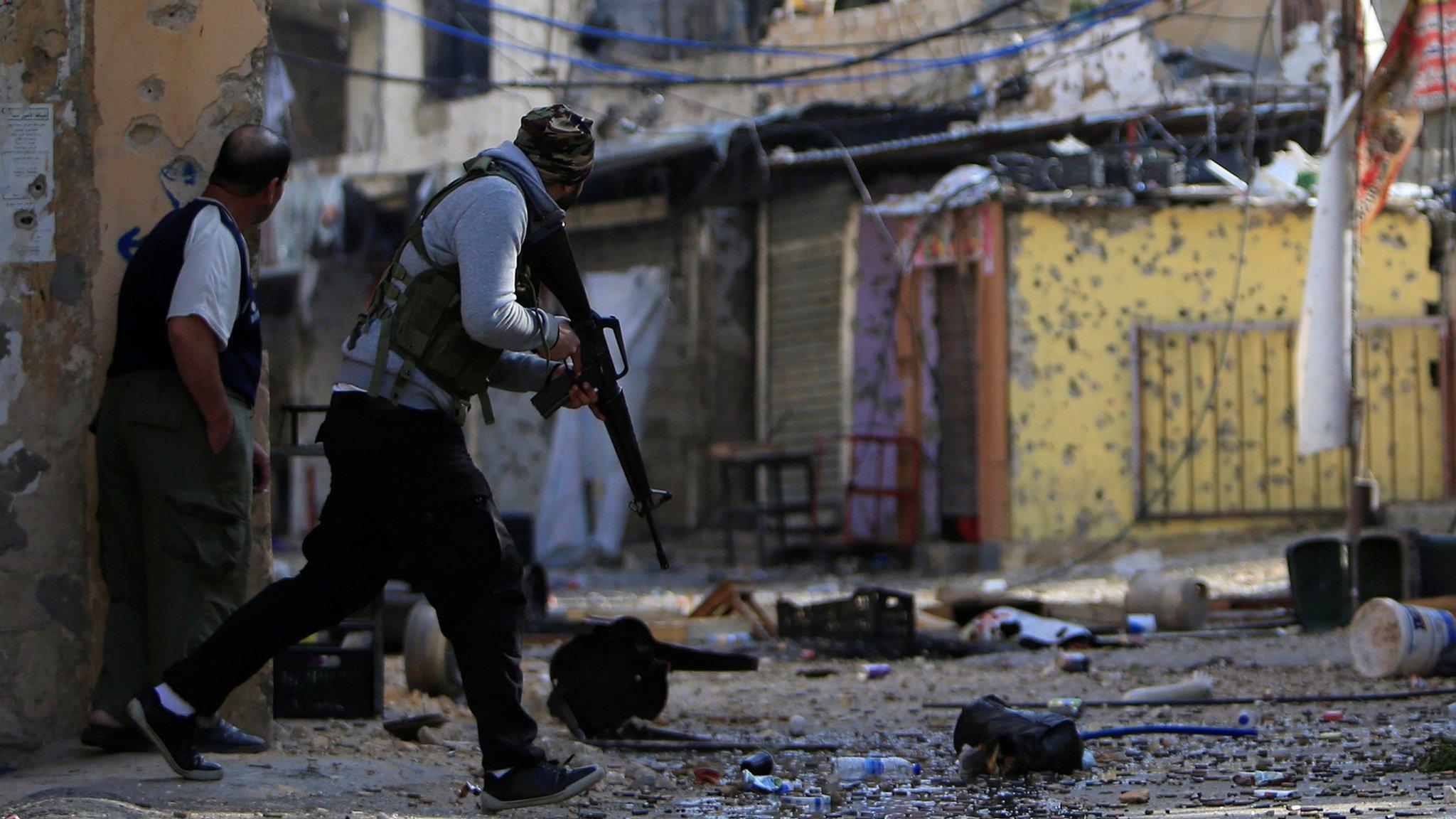 Palestinian gunmen from the Fatah faction attempt to cross a street during clashes in the Ein el-Hilweh refugee camp in Lebanon on 10 April 2017