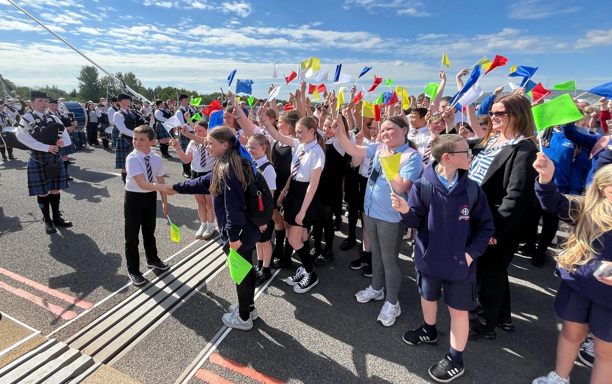 Children waving flags in the middle of a bridge. Two children are shaking hands