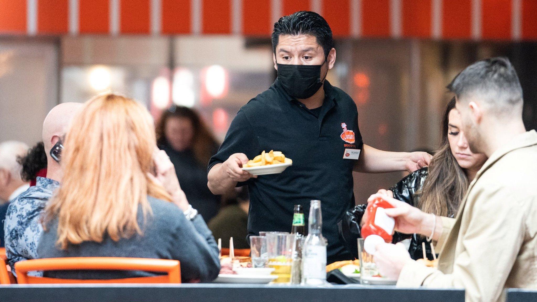 A waiter serves food at a restaurant near Times Square in New York City, U.S., December 16, 2021.