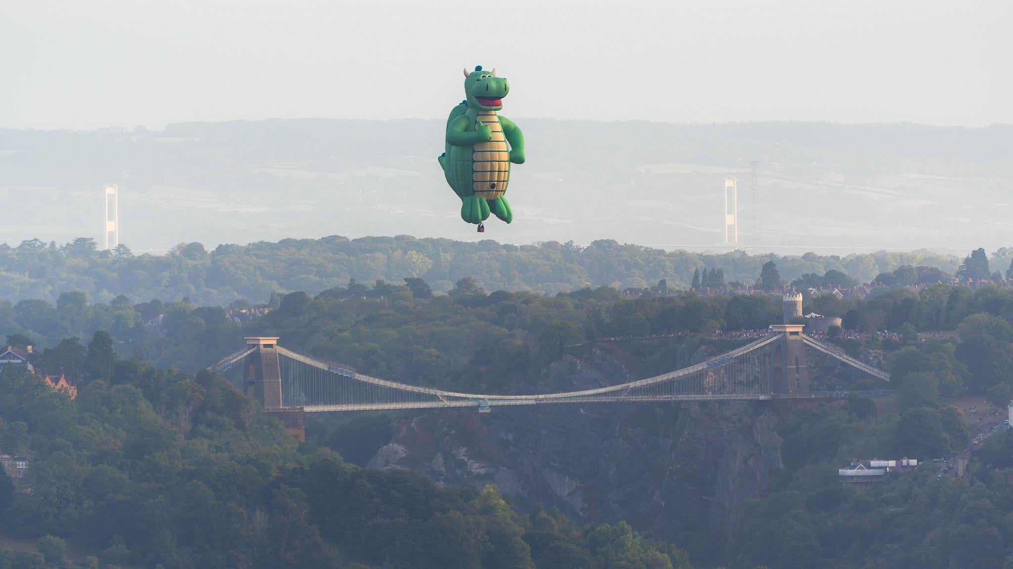 A dragon-shaped hot air ballloon flying above the Clifton Suspension Bridge in Bristol.