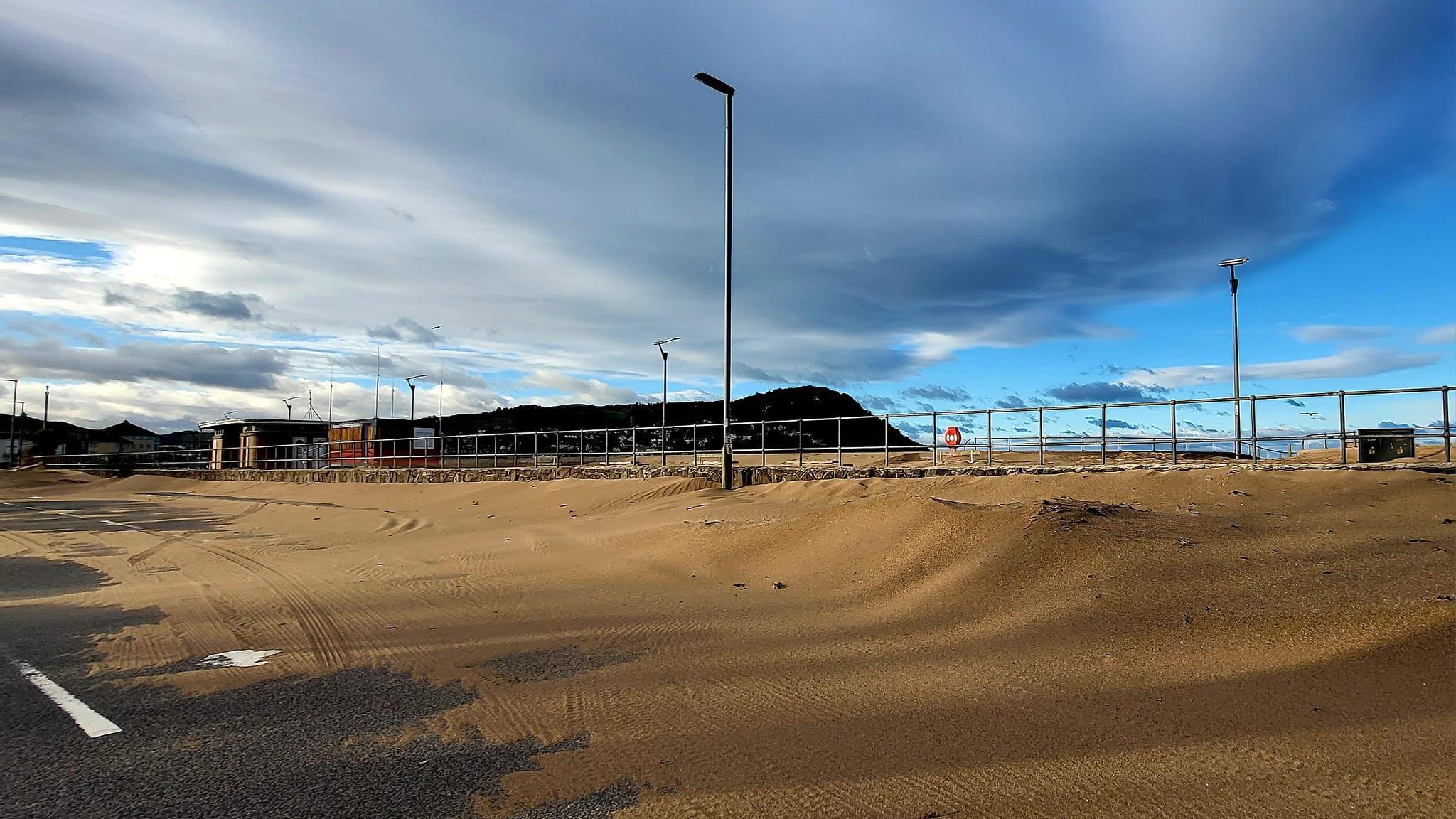 A road near Minehead beach is covered in sand after a storm swept the sand away.