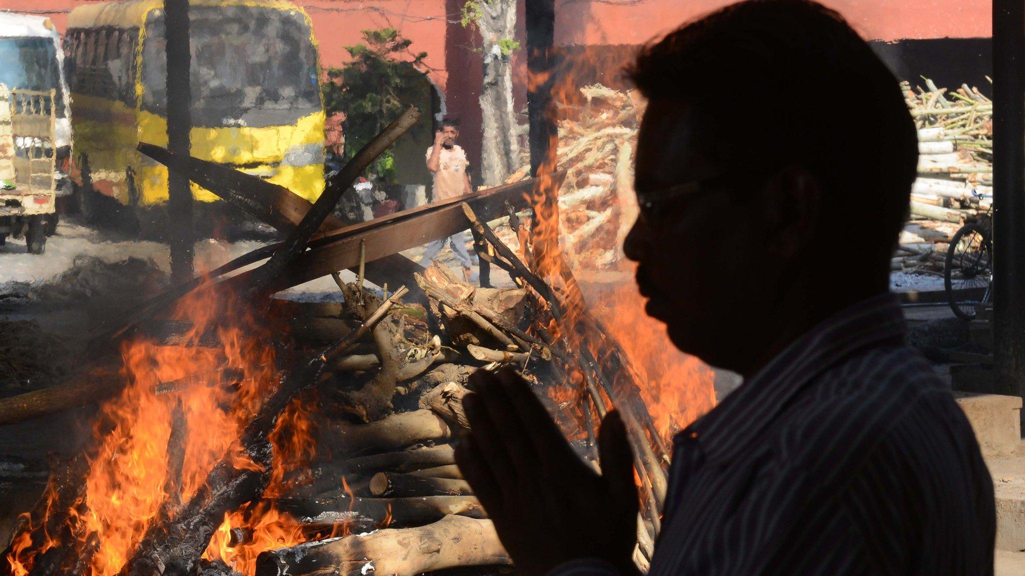 A relative pays his respects as he stand next to the burning pyres of Sarvesh, who was killed when a train ploughed into a crowd of revellers during Dussehra festival celebrations on October 19, at a cremation ground in Amritsar on October 21, 2018