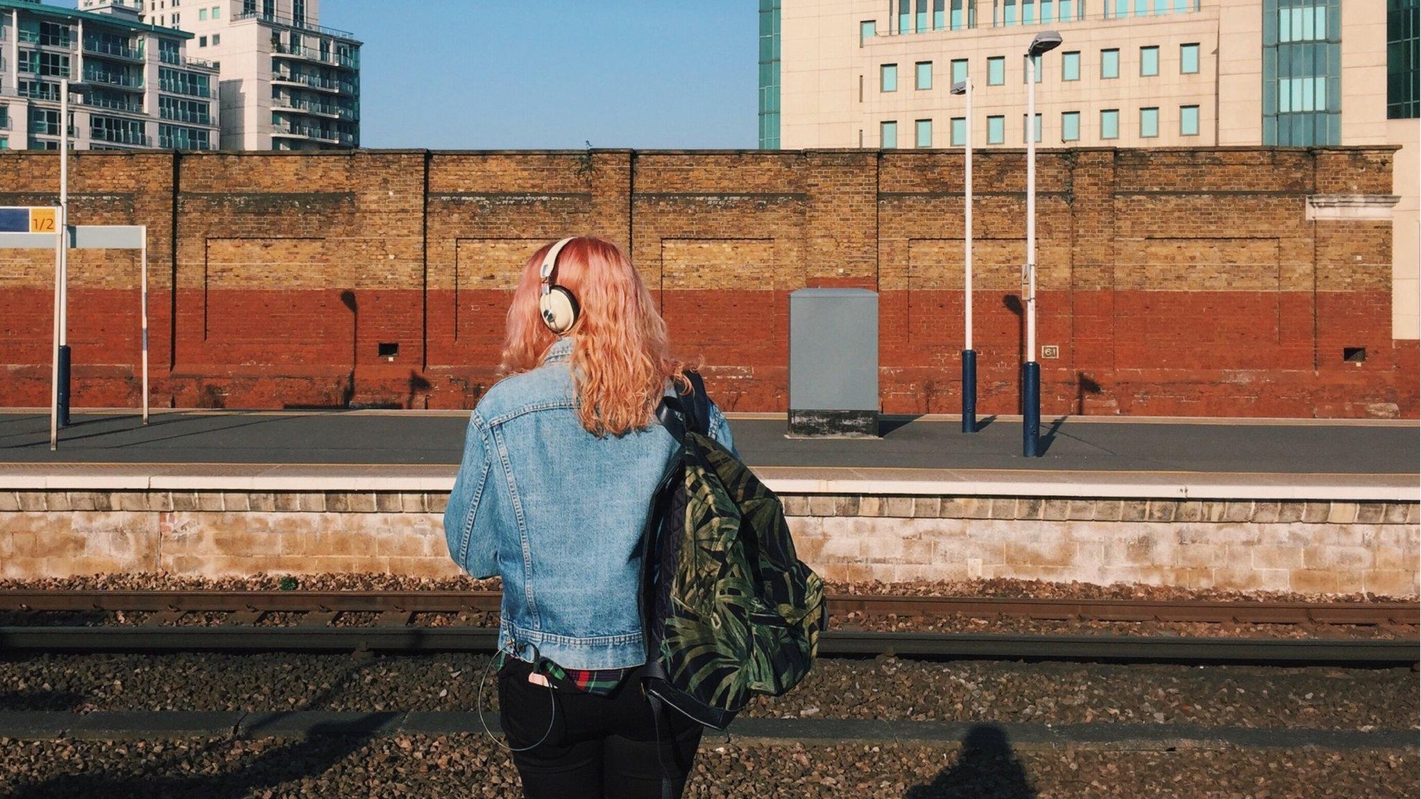 A woman waits at a train platform