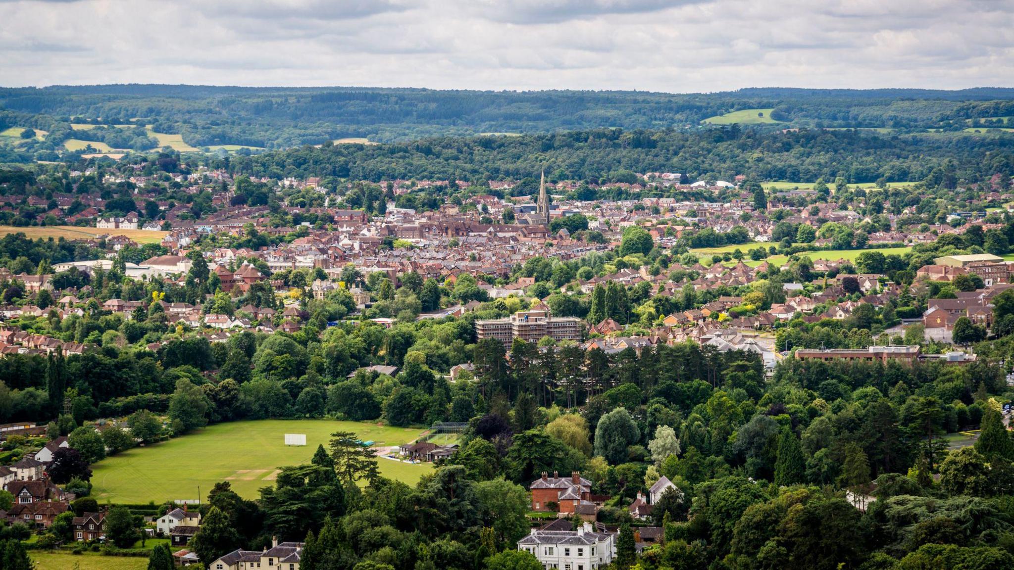 An aerial view of Dorking with a church seen in the middle and green hills surrounding it