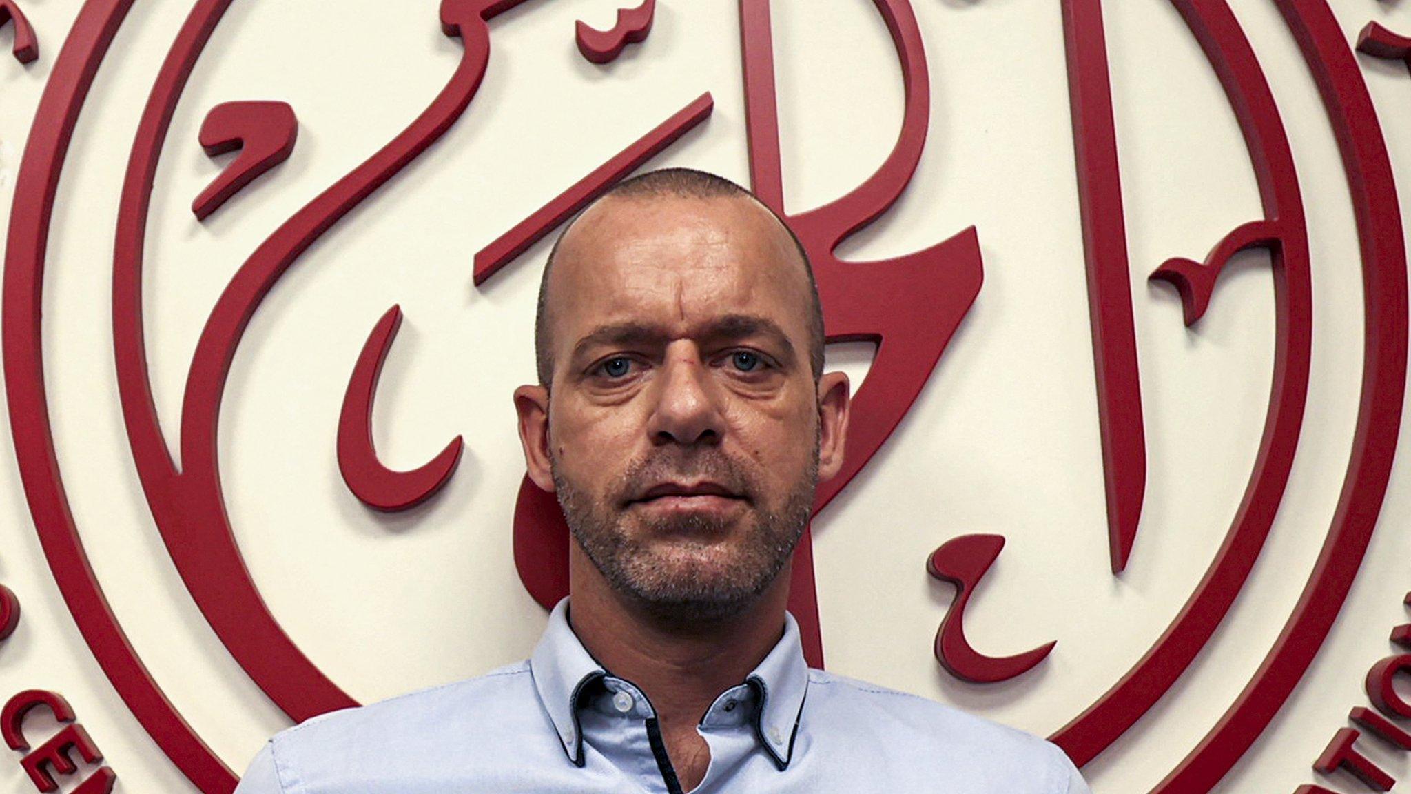 Salah Hammouri, French-Palestinian human rights lawyer, stands in front of the logo of the human rights group al-Haq, in Ramallah, in the occupied West Bank (8 November 2021)