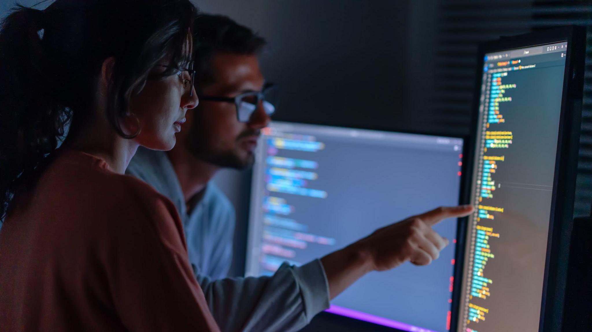 Two coders look at a screen