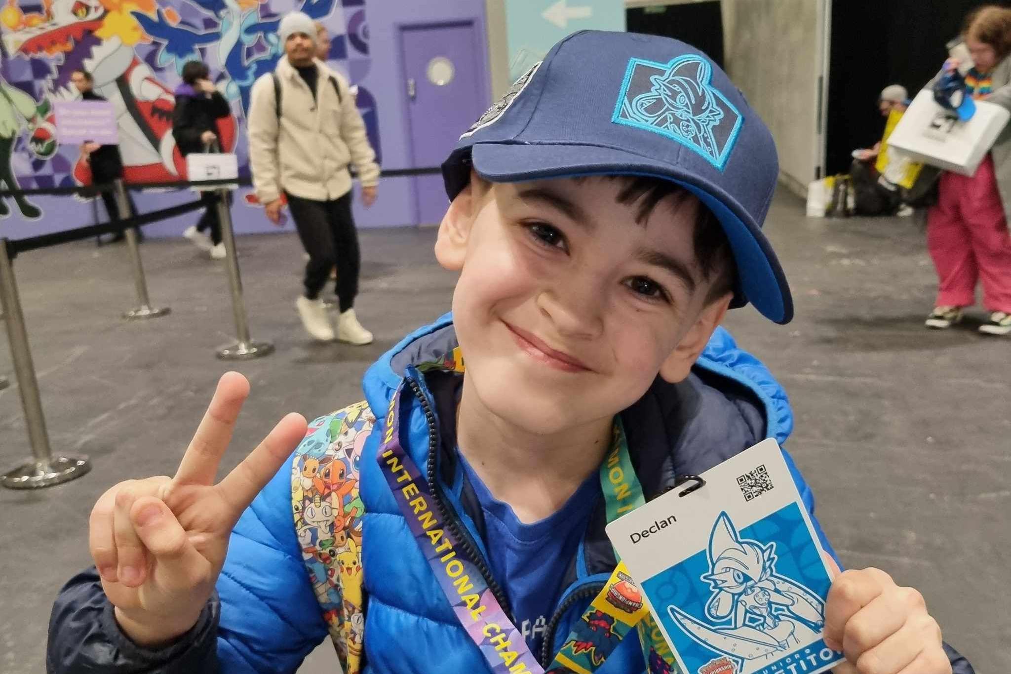 Declan poses with a peace sign and a competitors badge from one of his competitions  