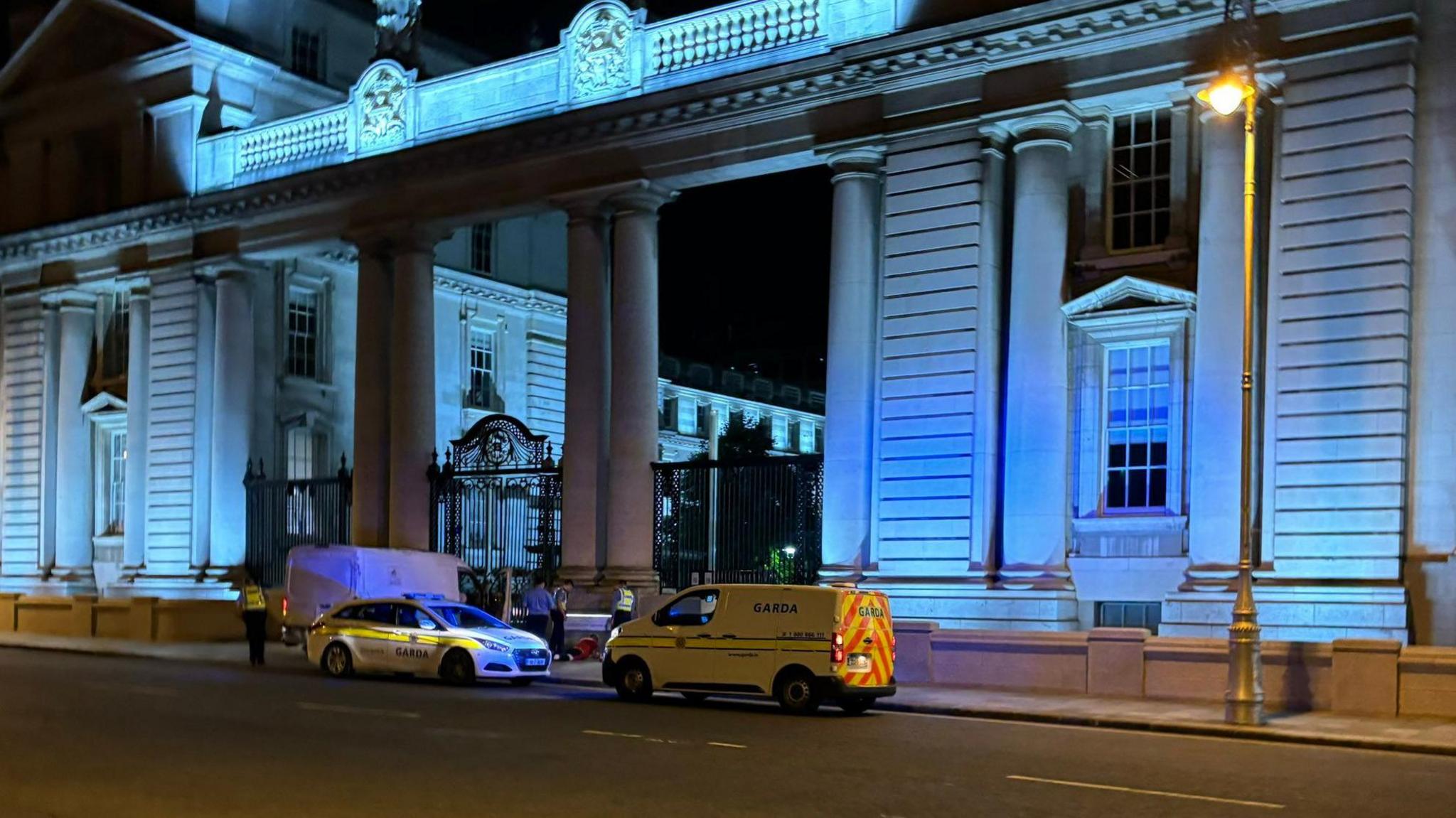 Gardaí detaining a man next to a white van outside Government Buildings