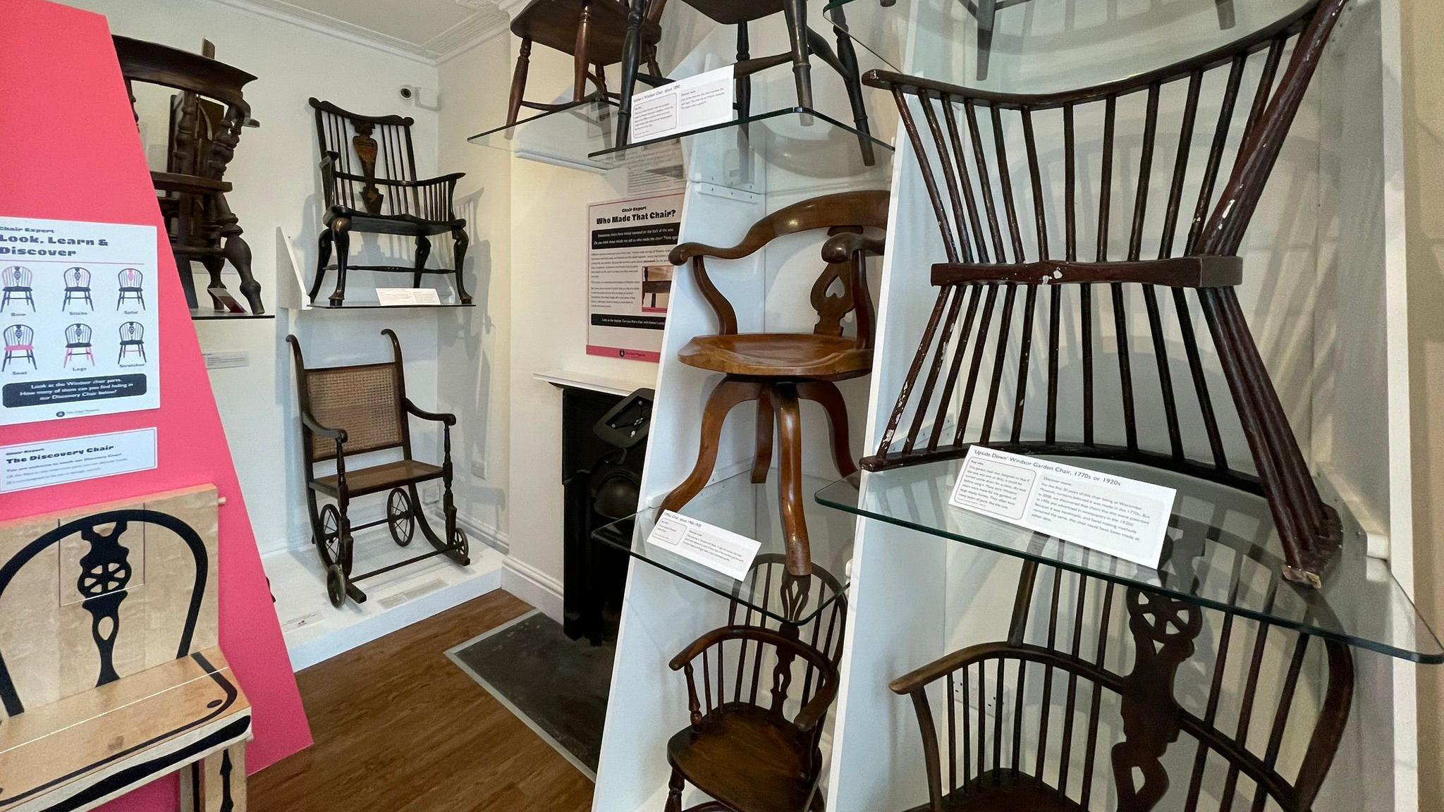 A selection of old-fashioned wooden chairs on display in a museum 