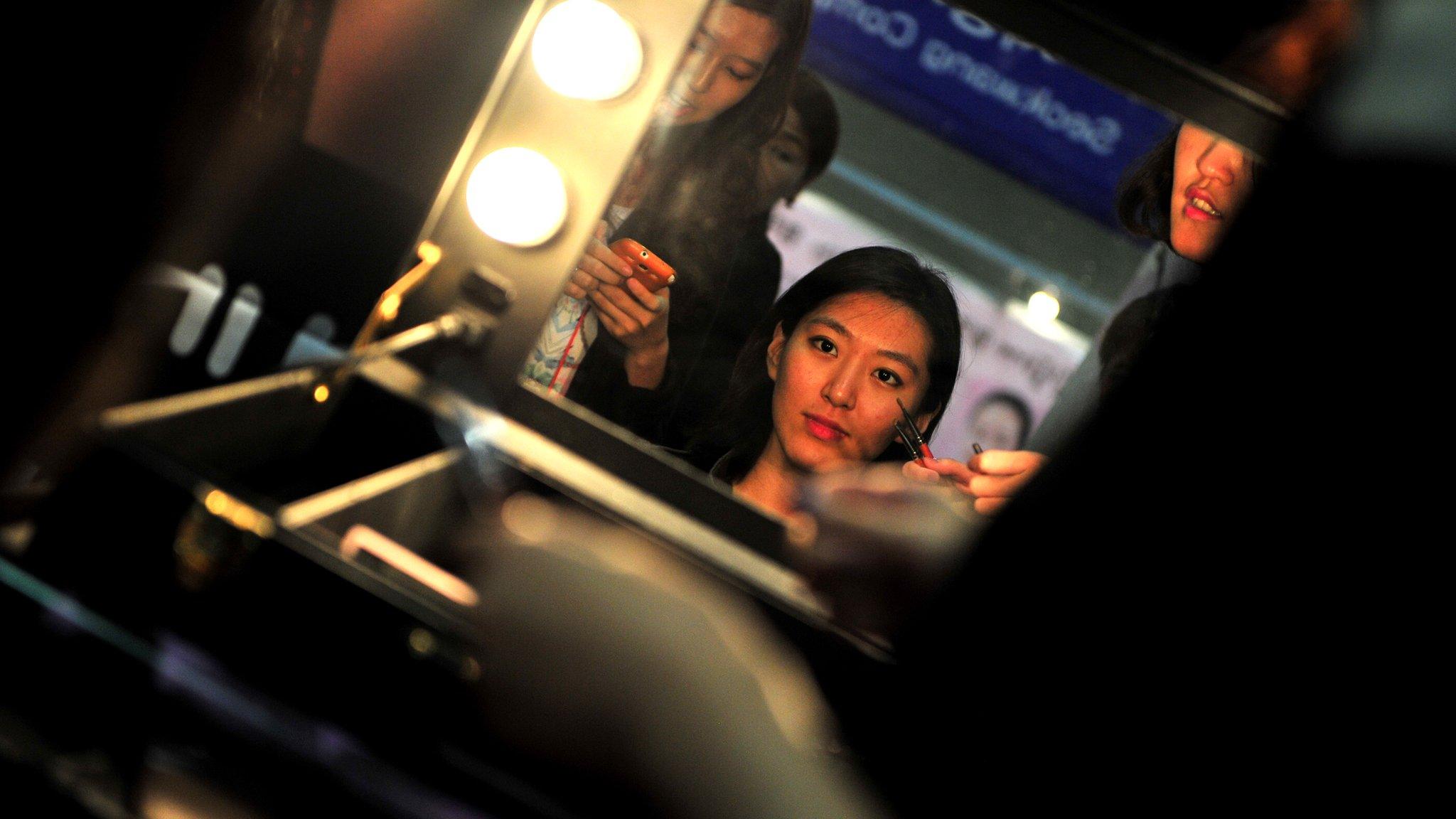 A customer (C) is attended to by a make-up artist (R) during the 5th Korea Beauty and Cosmetic Expo in Goyang, north of Seoul on September 14, 2013