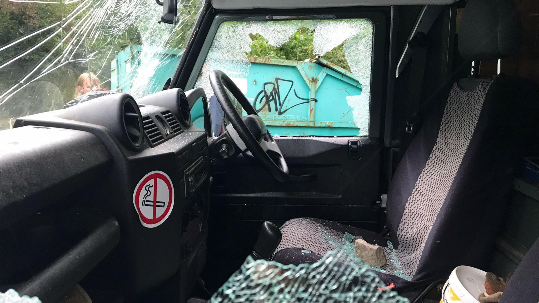 The inside of a Land Rover with smashed glass and a rock on one of the seats.