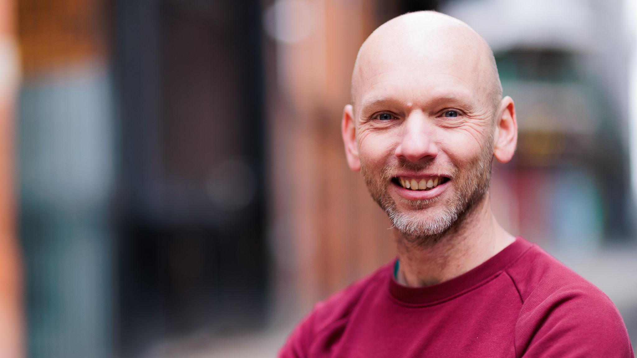 John Rostron in a red t-shirt, smiling