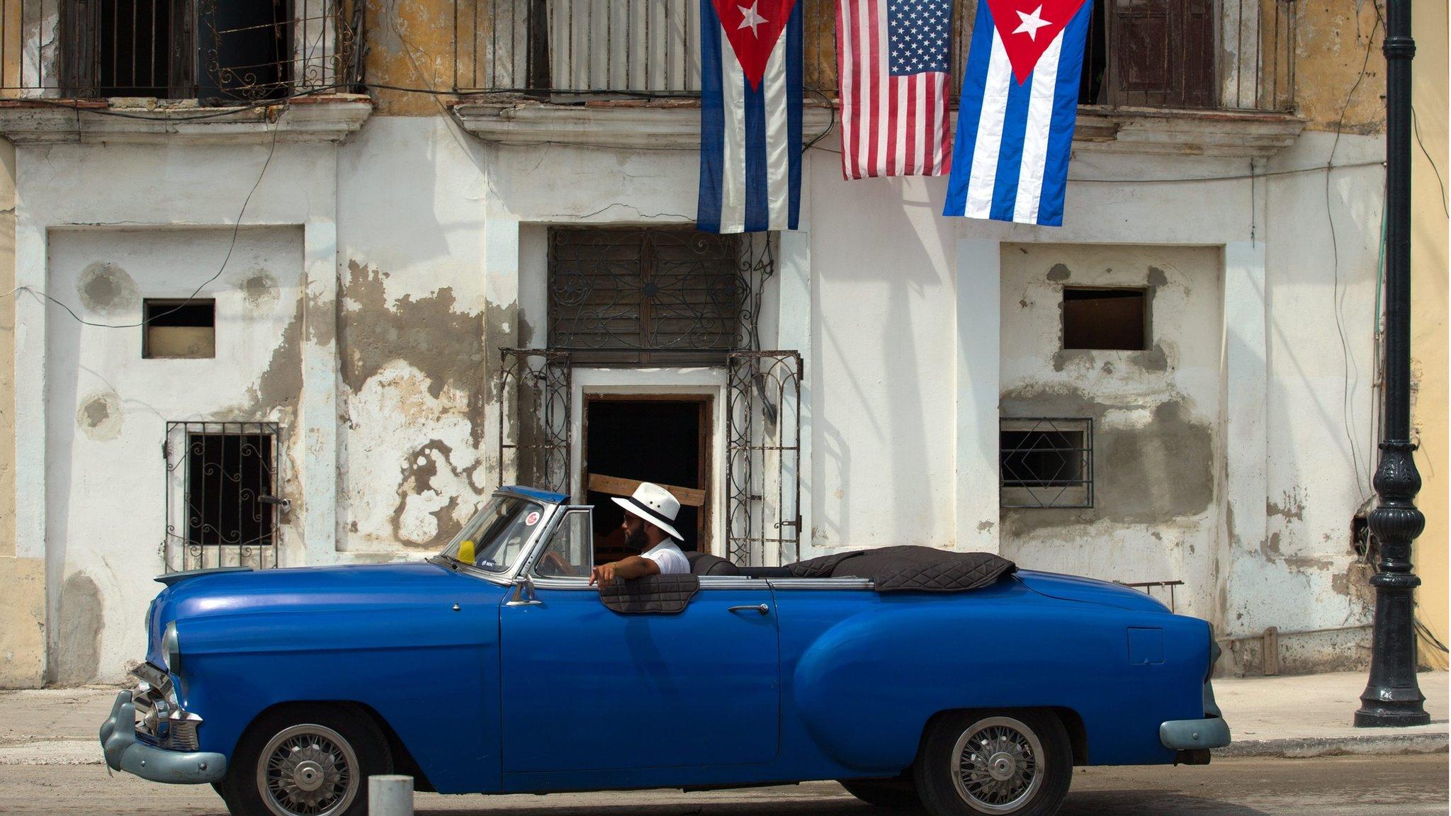 An old car passes by a house decorated with American and Cuban flags in Havana, Cuba (20 March 2016)