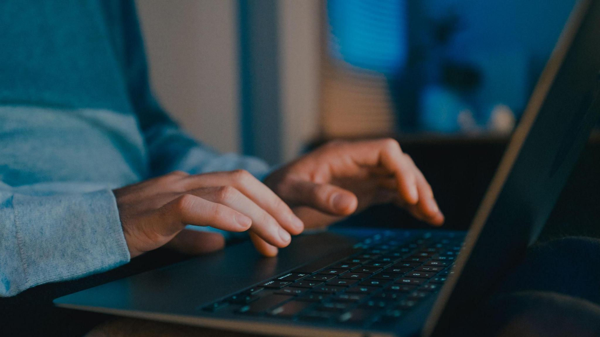 Hands typing on a laptop