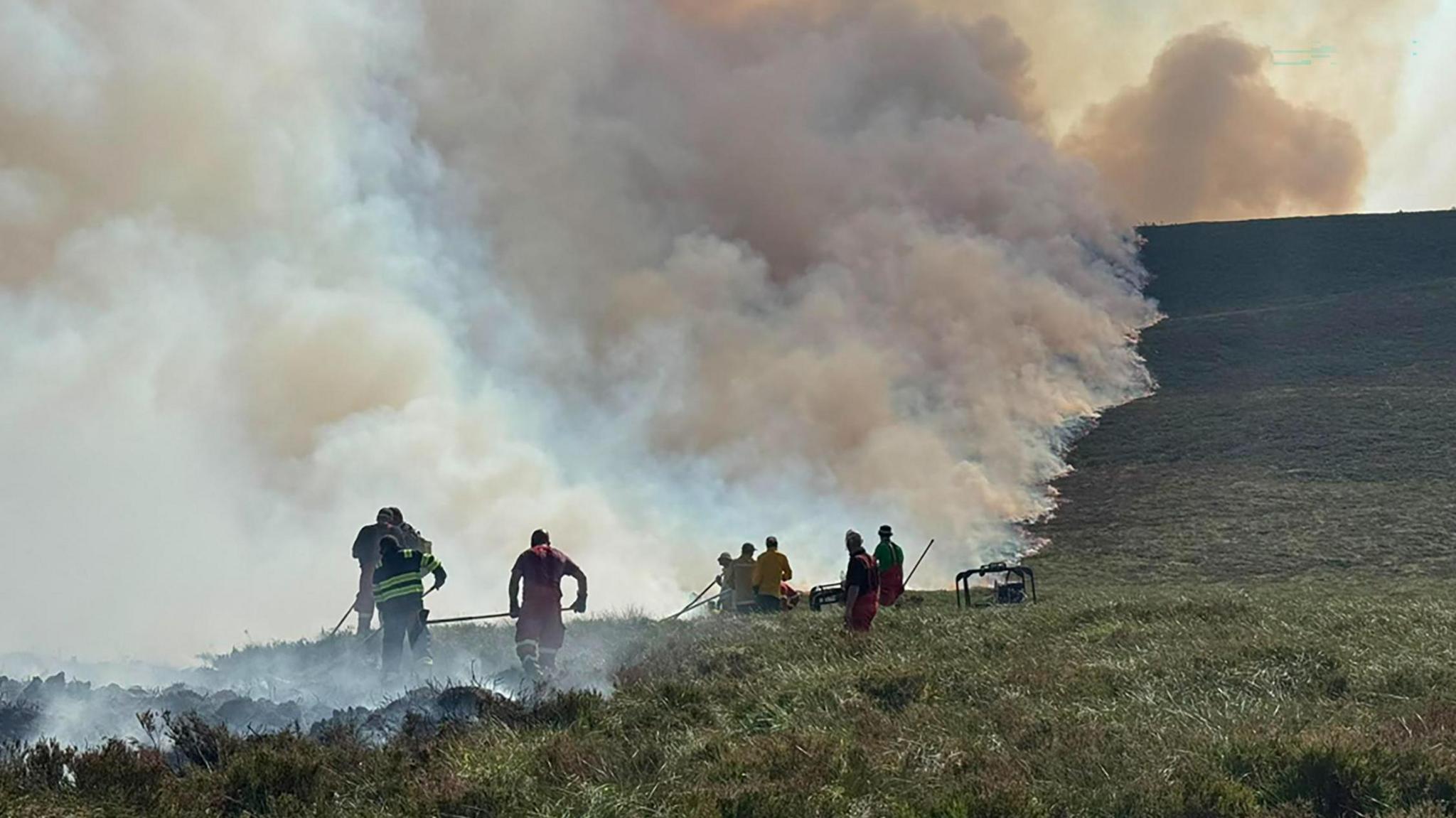 several people beating down smoking grass on a hillside