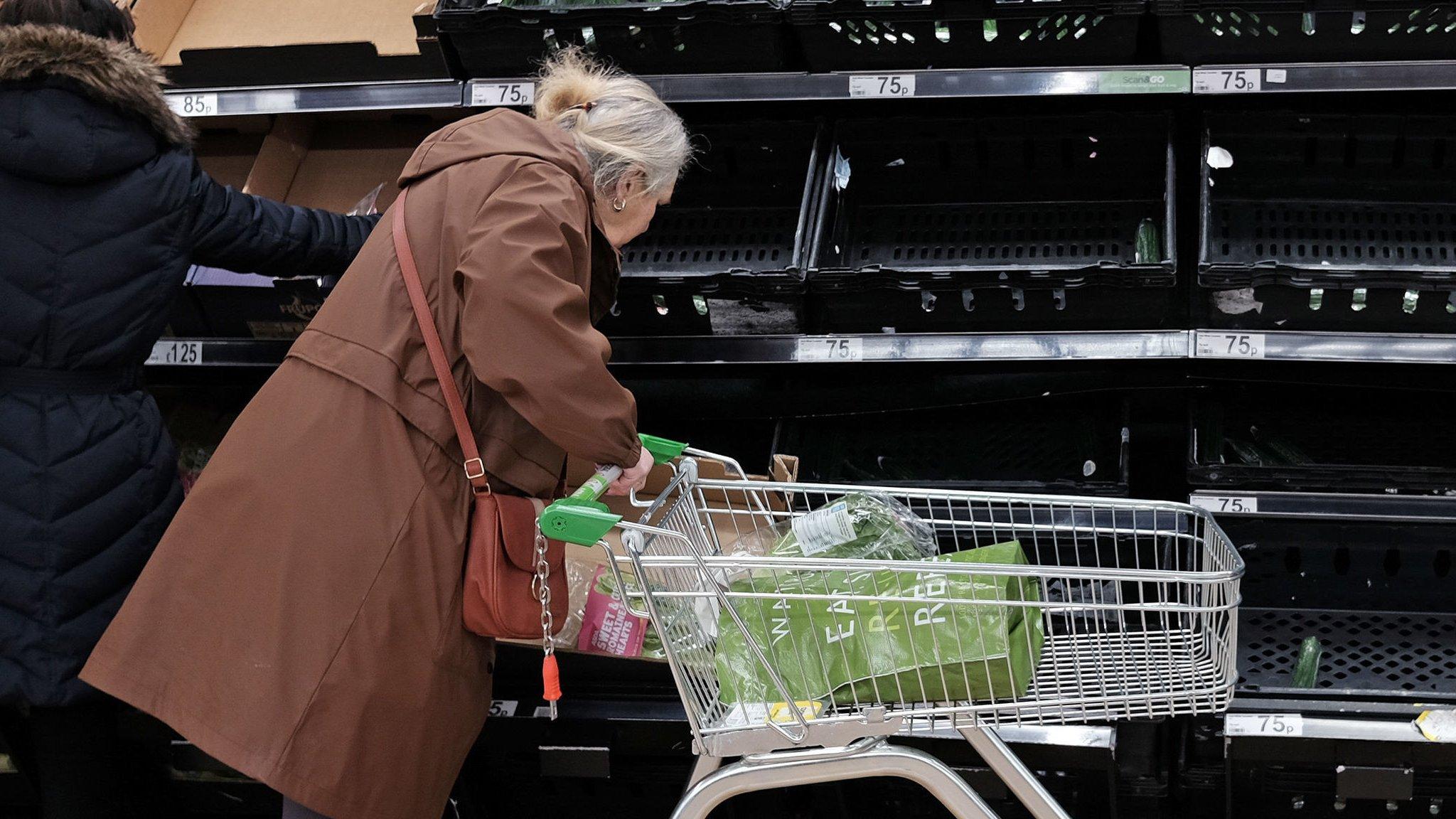 Woman in front of empty veg shelves