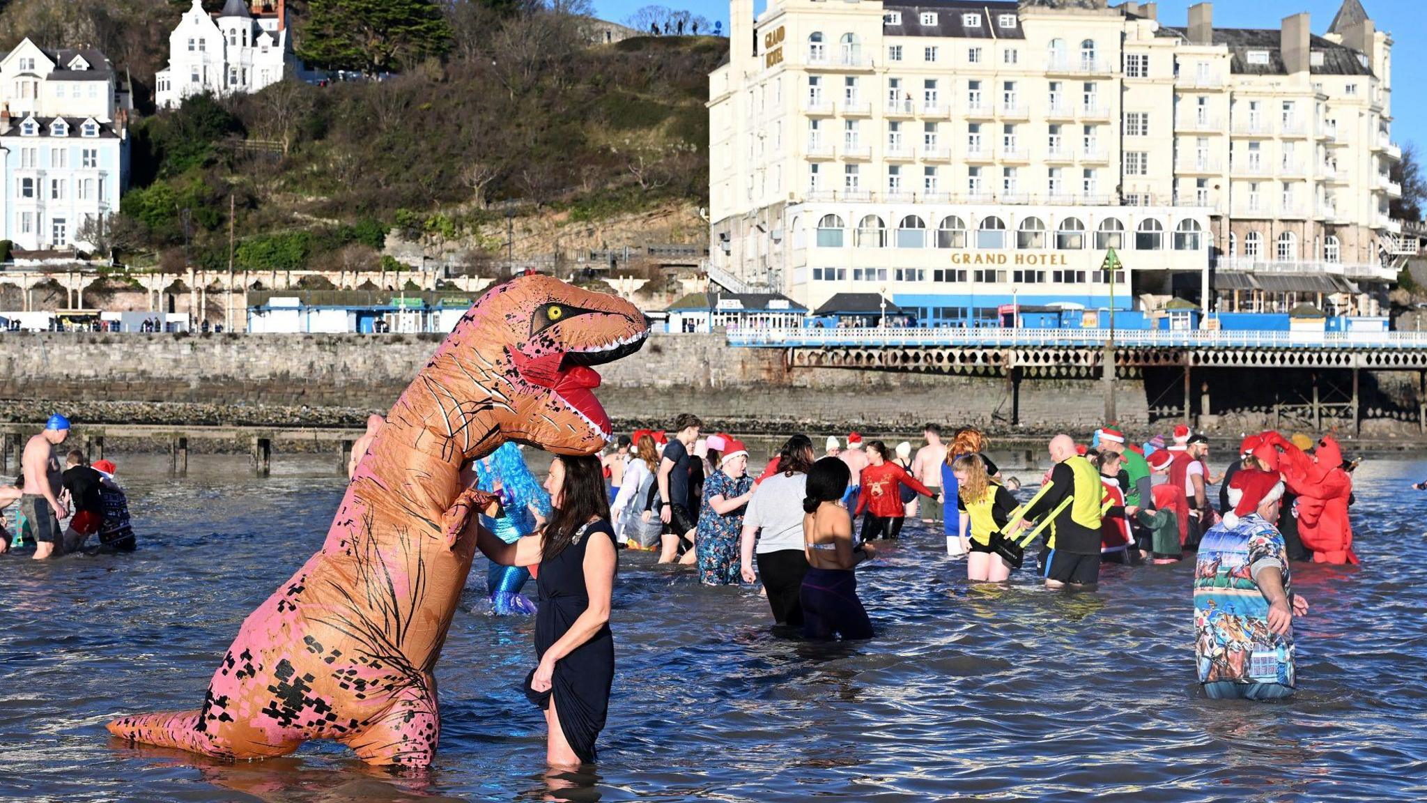 A person dressed as a T. rex off the coast of Llandudno