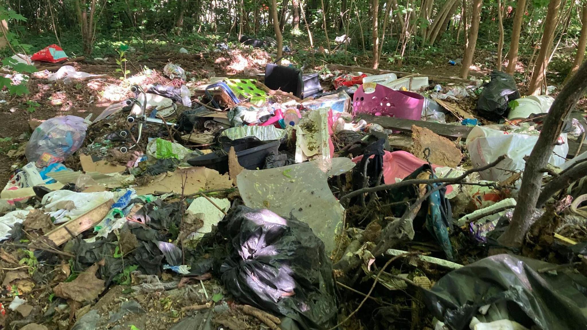 Piles of rubbish are scattered across woodlands including toys, bin bags and broken plastic chairs
