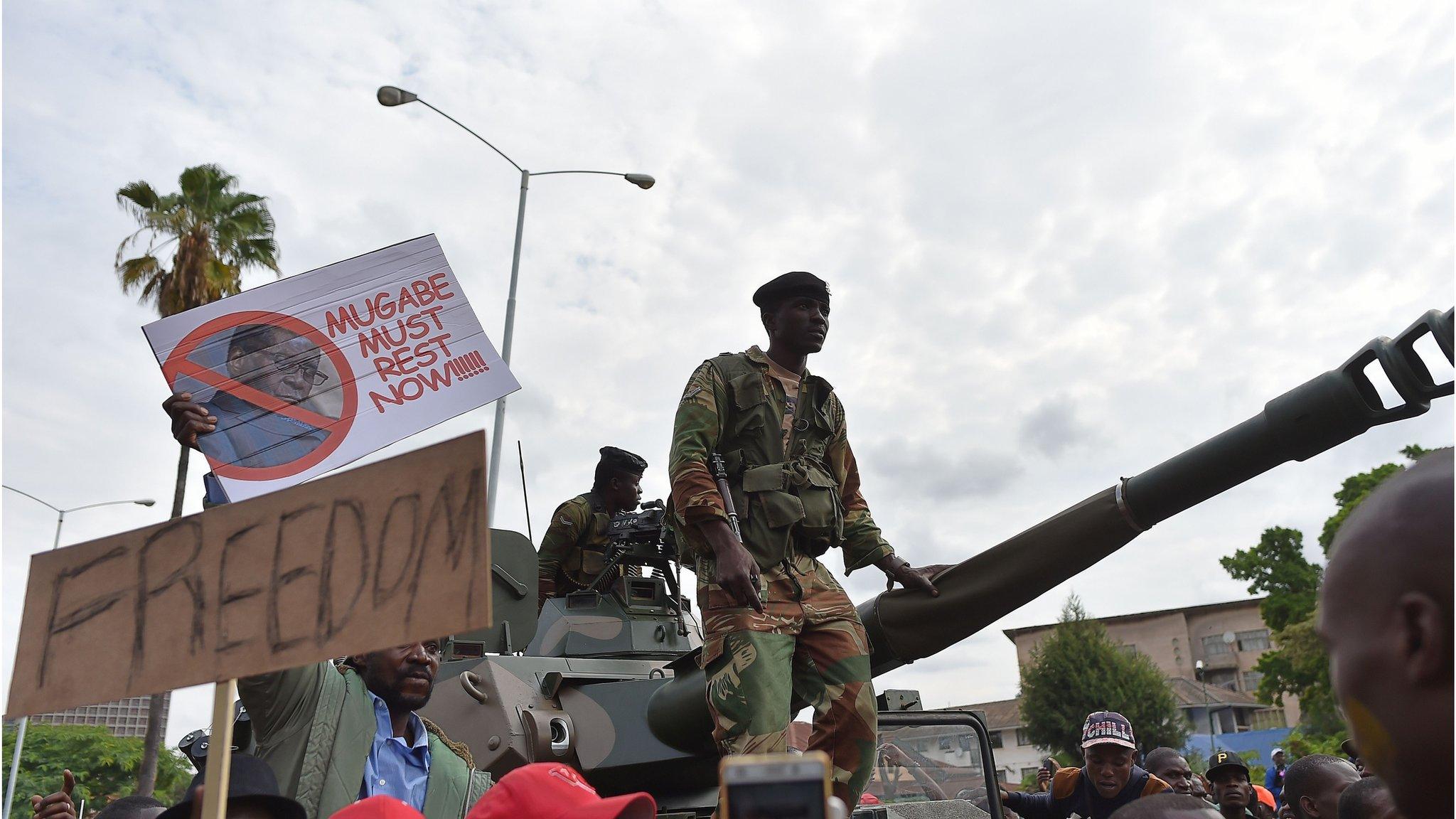 Zimbabwean Defence Force soldiers stand on a tank as they move forward through a crowd of people during a march in the streets of Harare.