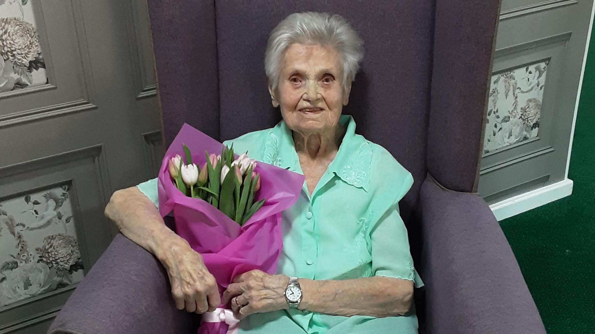 Lilian Ross sitting down holding a bunch of tulips