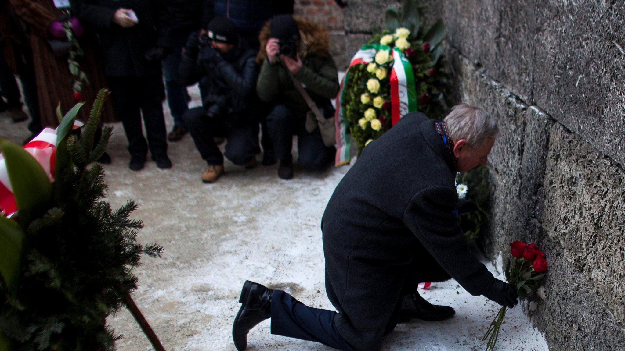 Survivor places flowers at the "death wall" in the former Nazi German concentration and extermination camp Auschwitz-Birkenau in Oswiecim, Poland