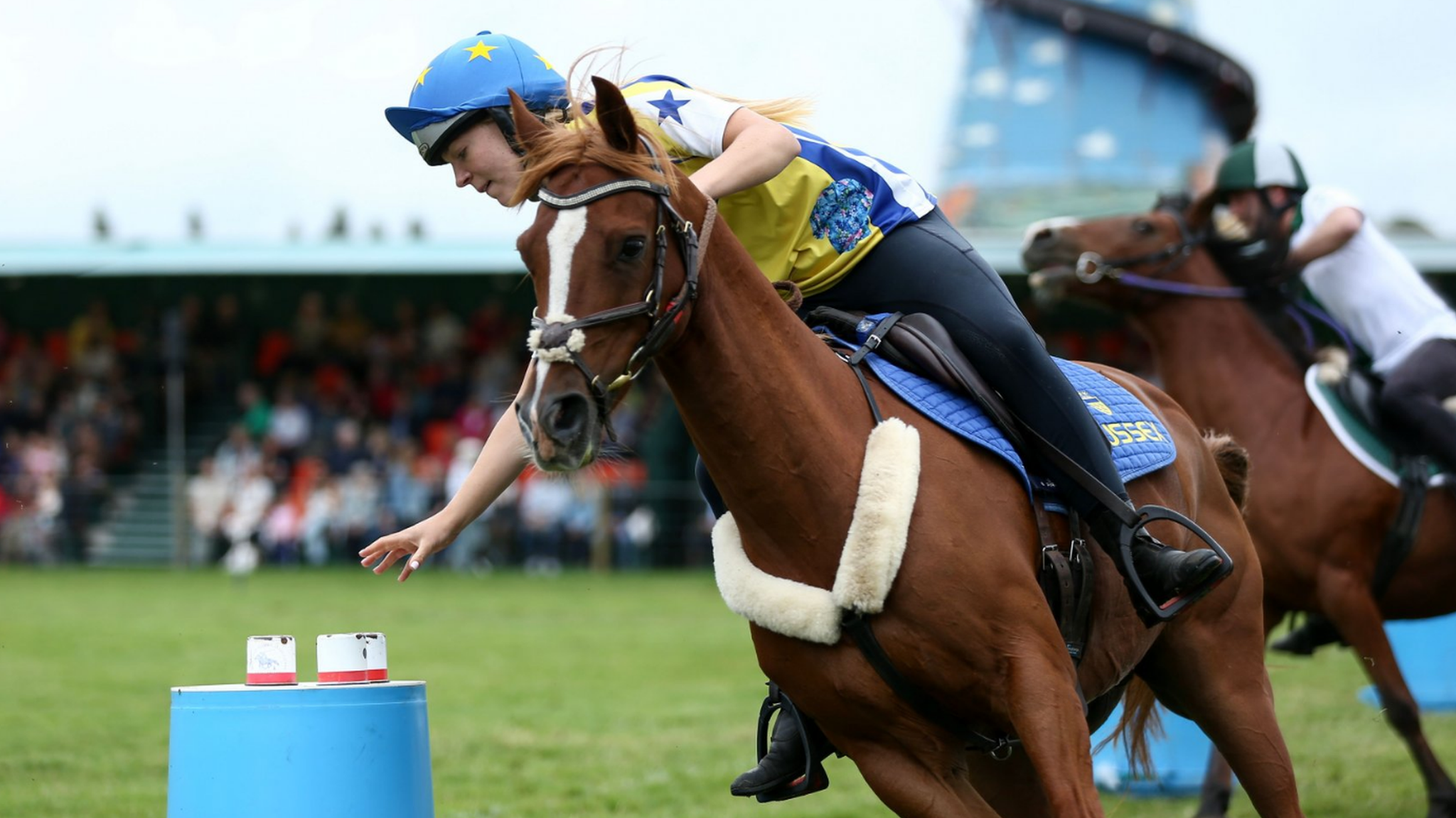 A rider reaches for an object during the Mounted Games - an agility and skills demonstration performed on fast ponies