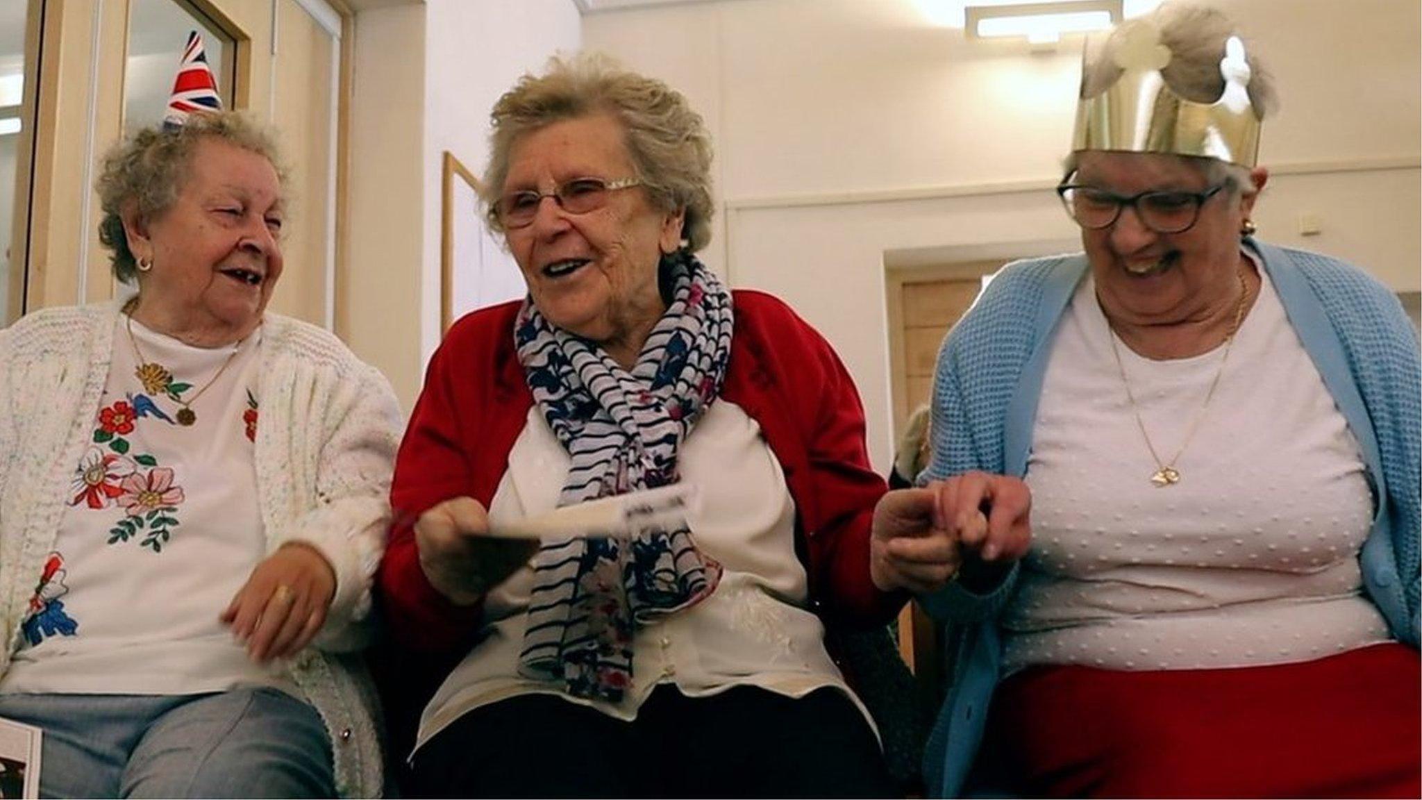 Three ladies smiling in a community centre room