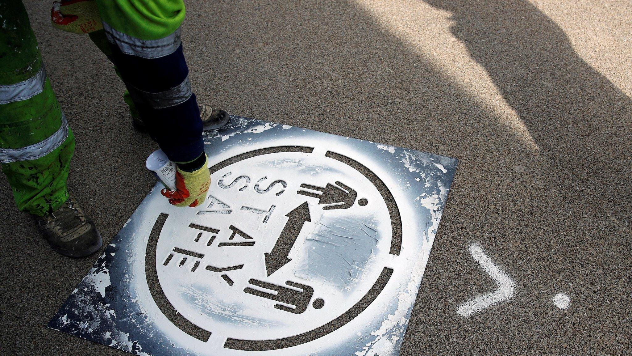 Council worker spraying social distancing "stay safe" sign