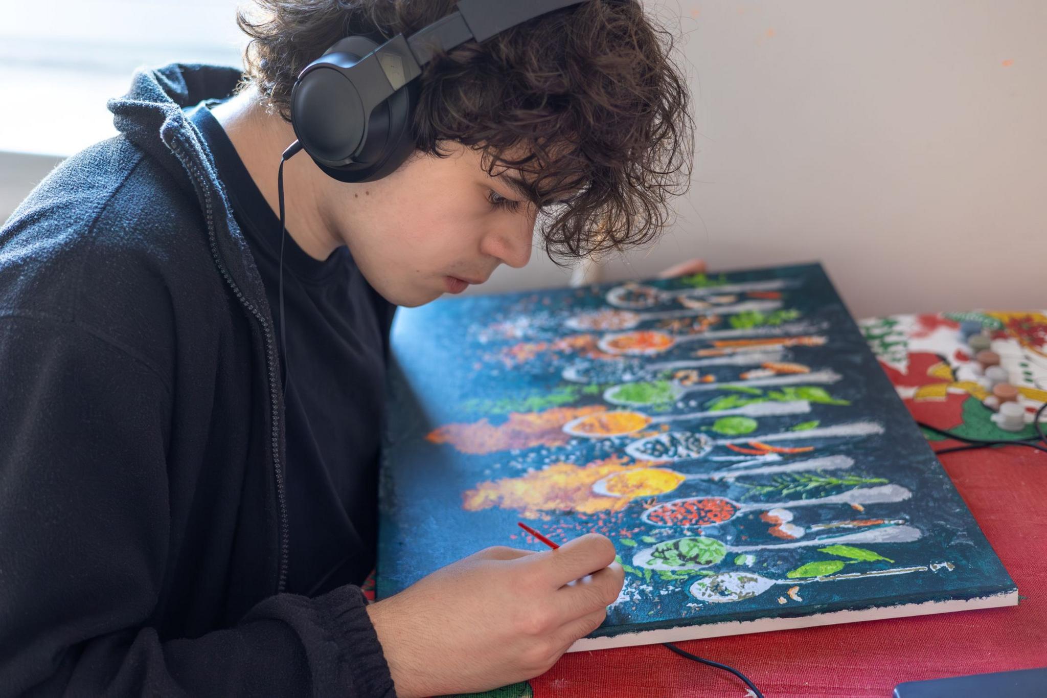 Teenage boy painting a colourful artwork at home