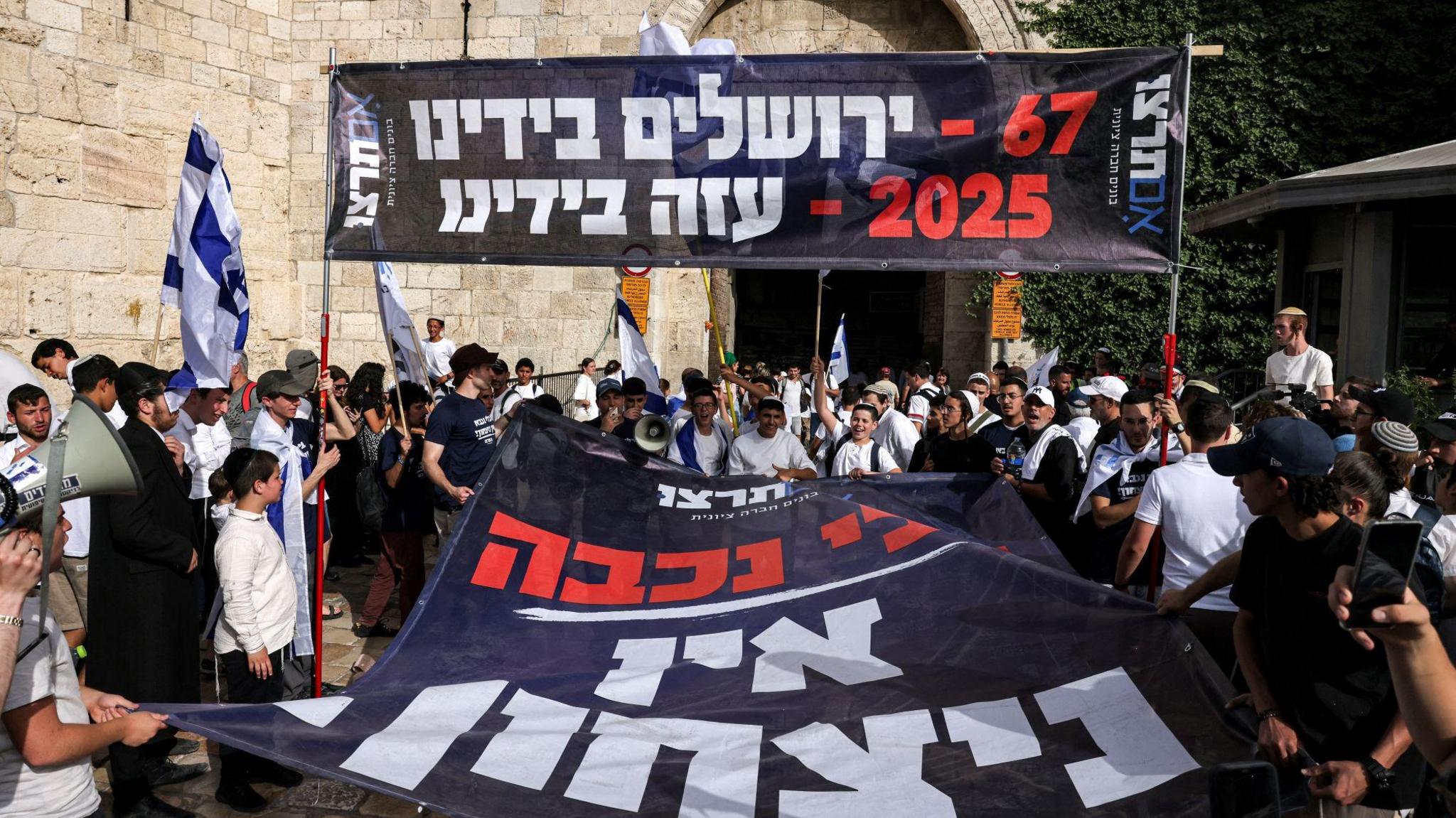 Right-wing activists hold a black, white and red banner saying "67 - Jerusalem in our hands; 2025 - Gaza in our hands."