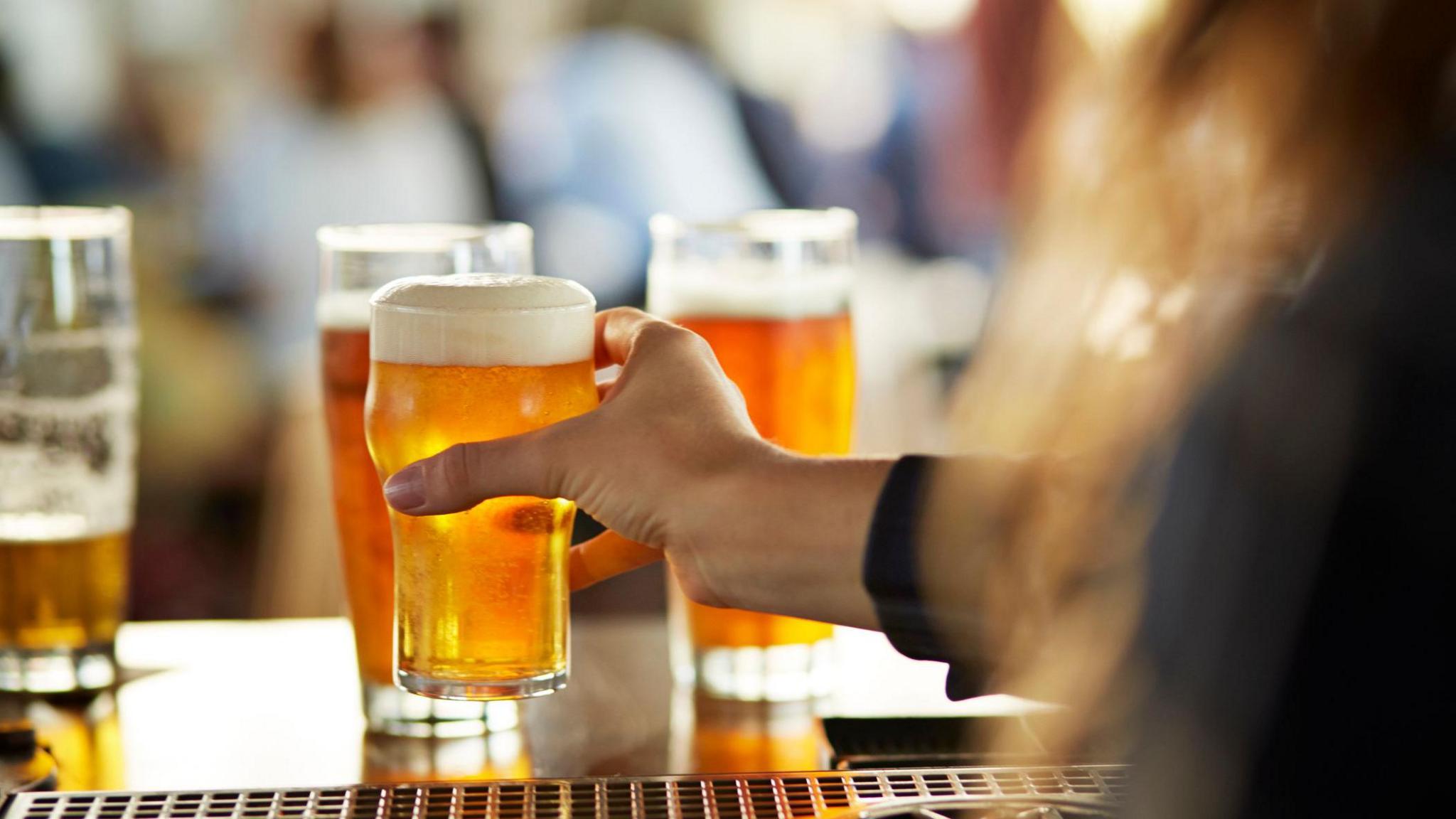 A hand on a pint of beer at a bar.