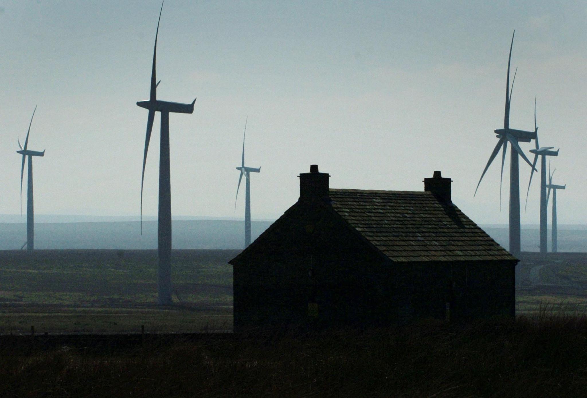 A Scottish cottage with turbines and the sea behind