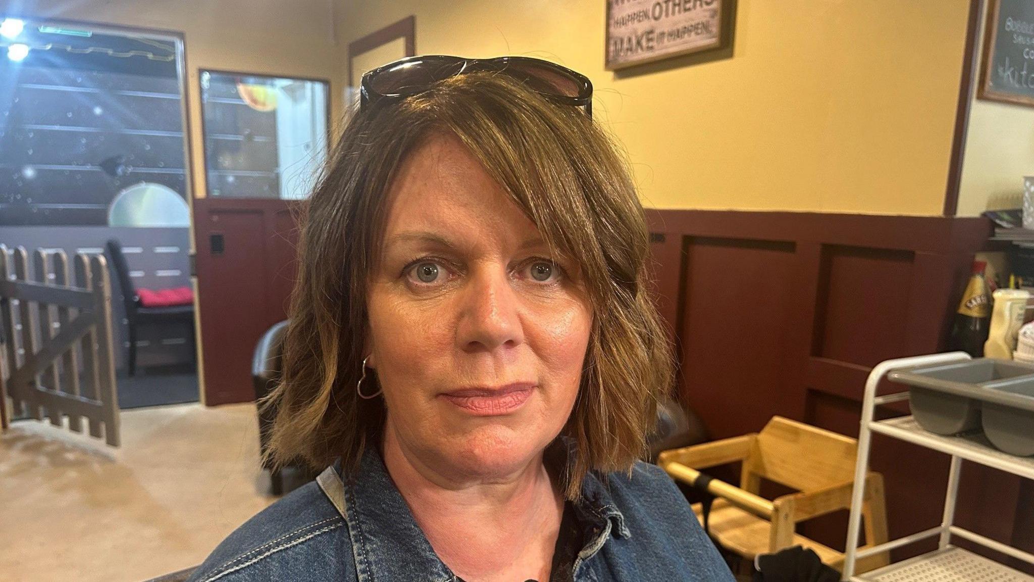 A woman with short brown hair with sunglasses on her head
