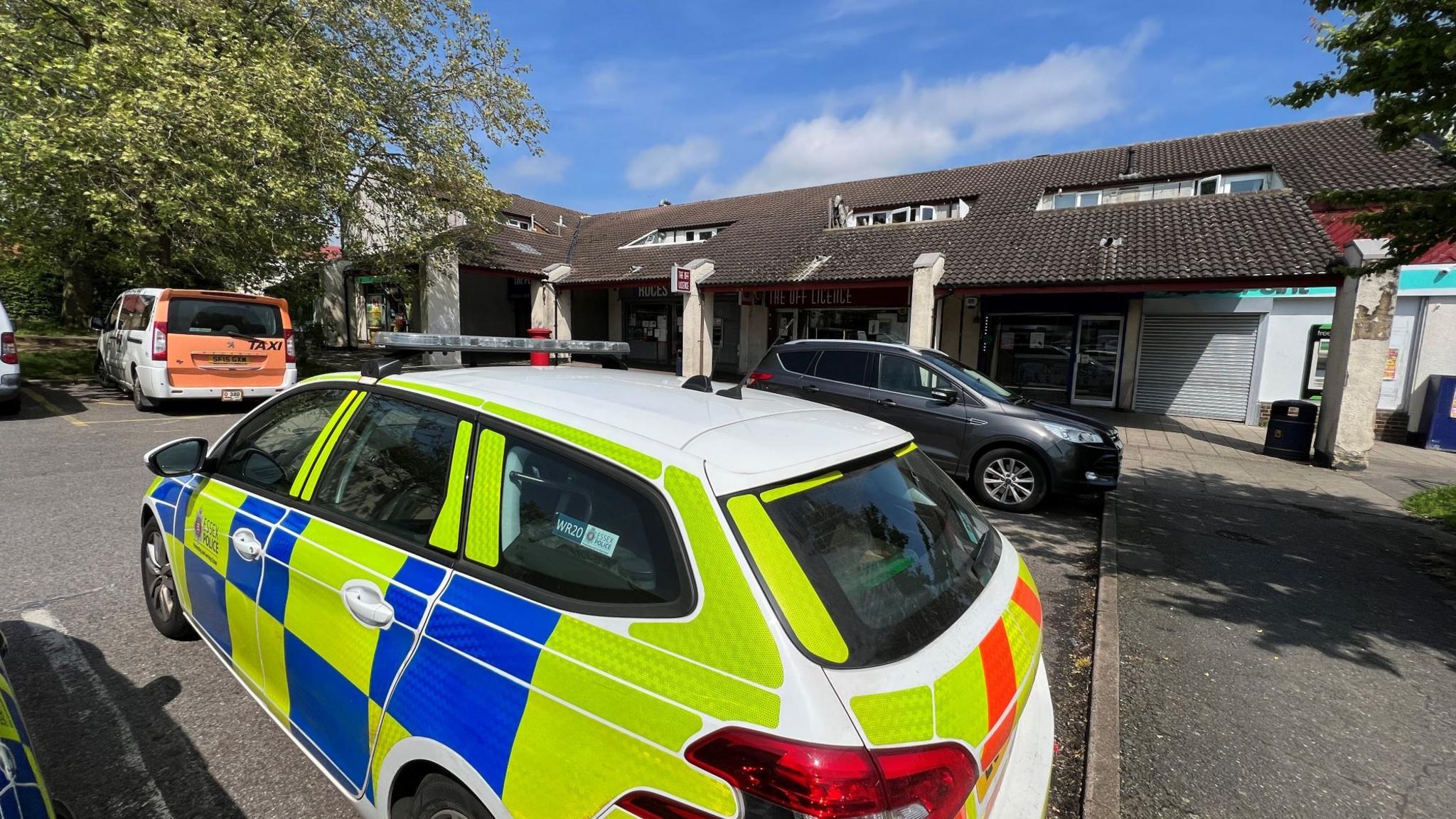 A police car parked outside a parade of shops