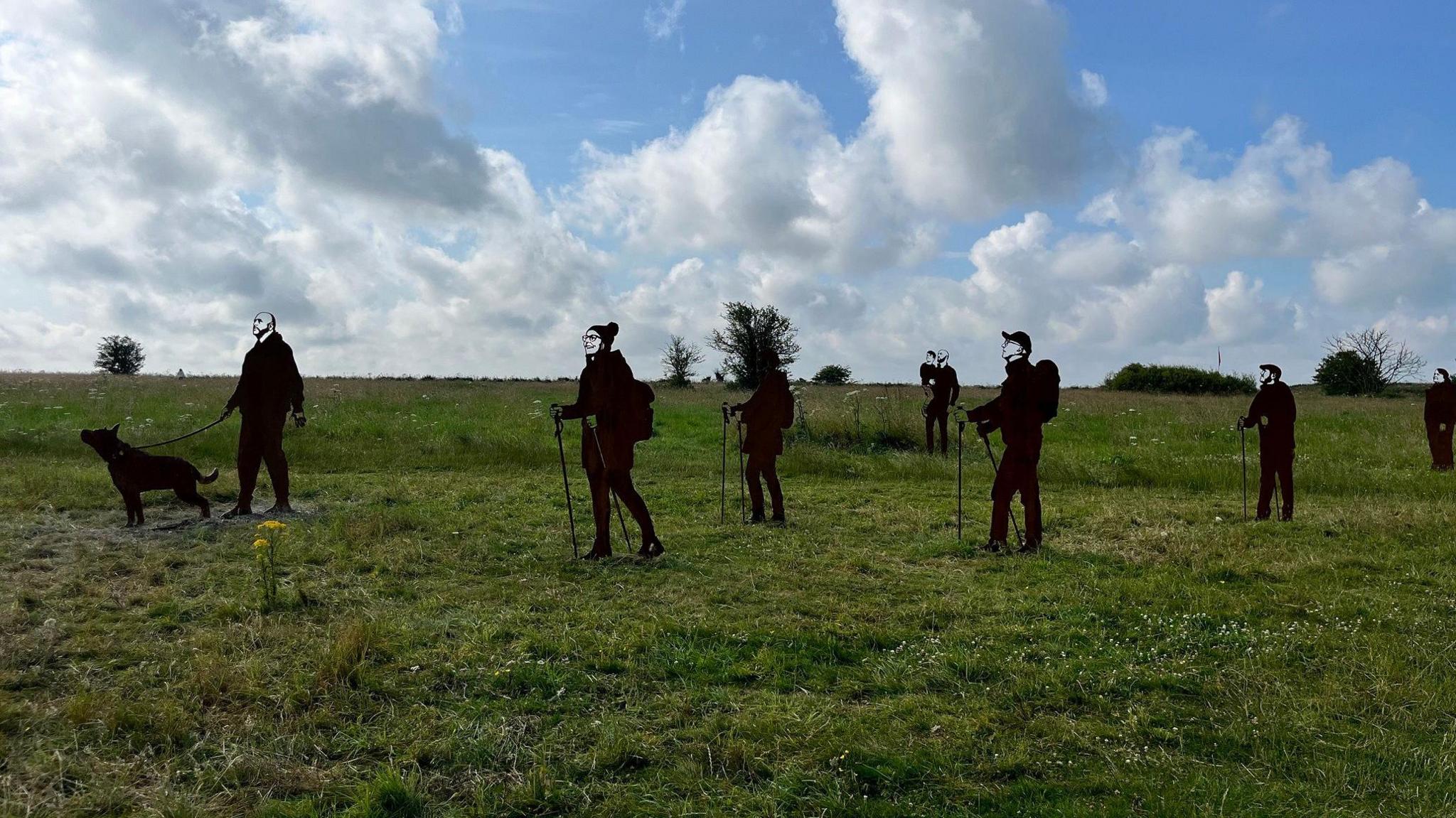 Statues representing members of the public who might want to walk on the land. One has a dog, and others have walking poles