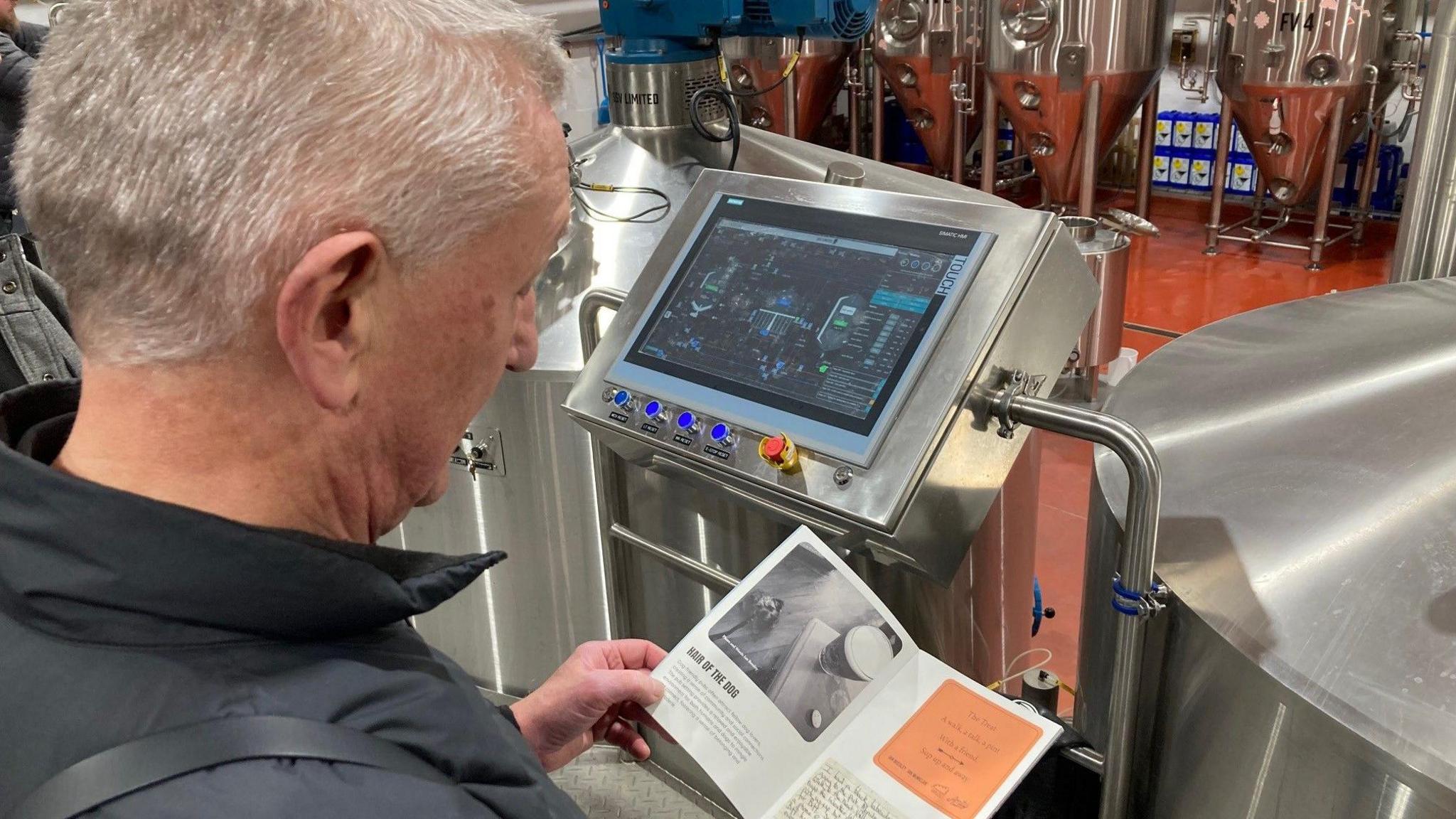 A man reading a pamphlet in a brewery 