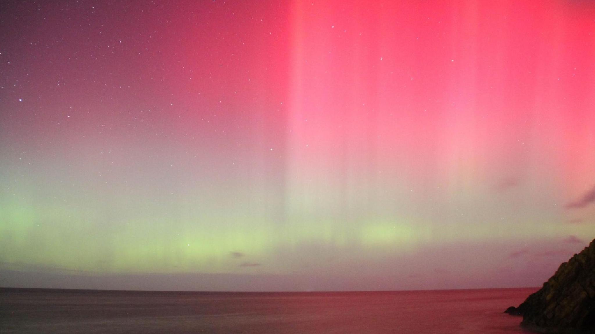 The horizon over the Irish Sea, from the west coast of the island, showing a strip of pale green and the pink sky above.