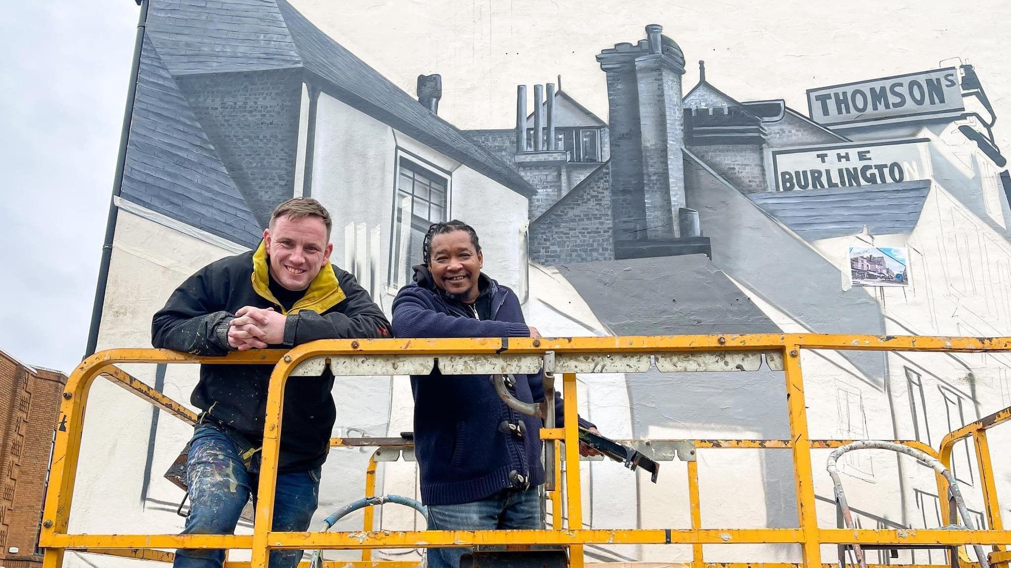 Nathan and Tony in a crane working on the mural