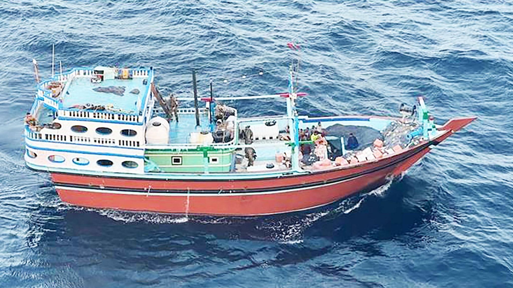 A colourful fishing boat surrounded by choppy sea.