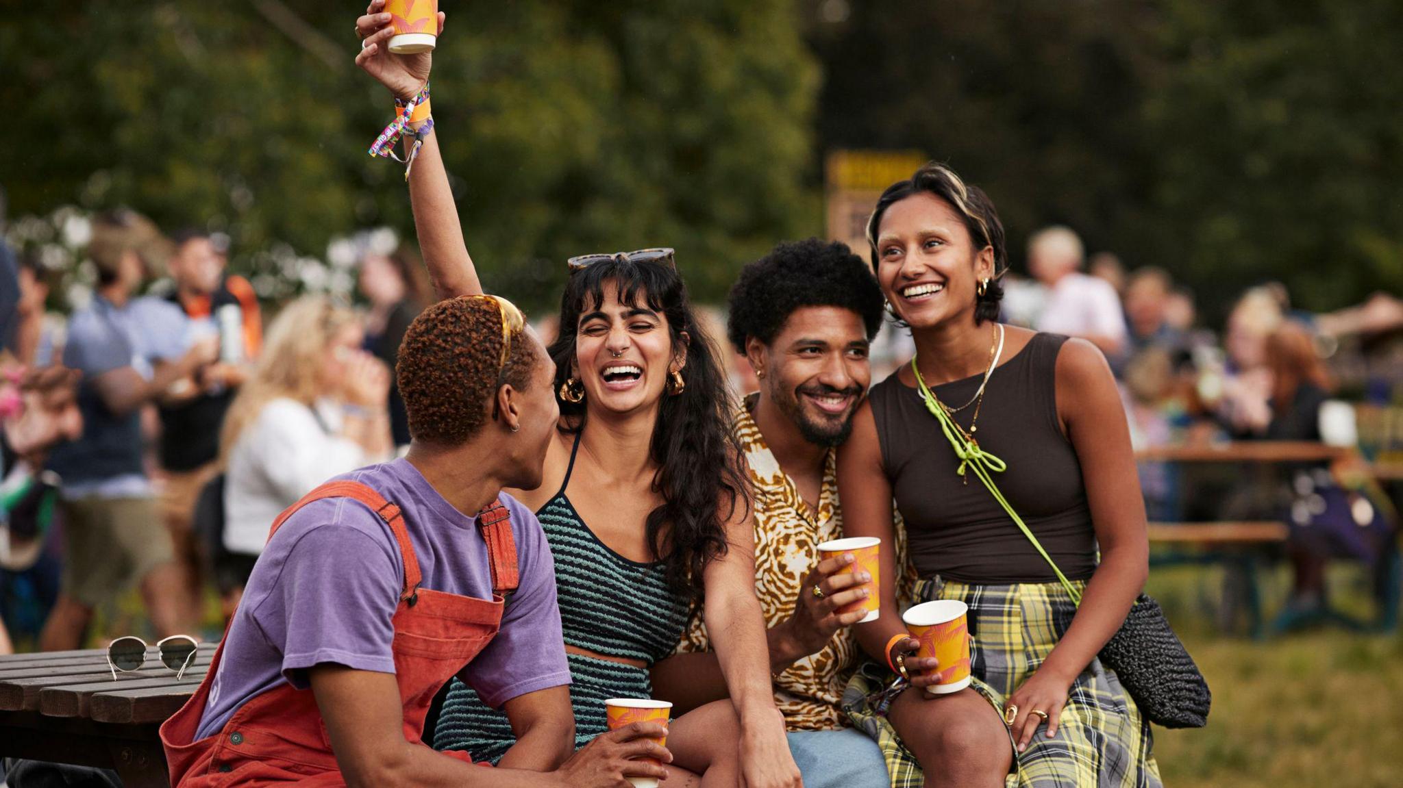 Four people sit happily together at a outdoor gathering drinking from cups