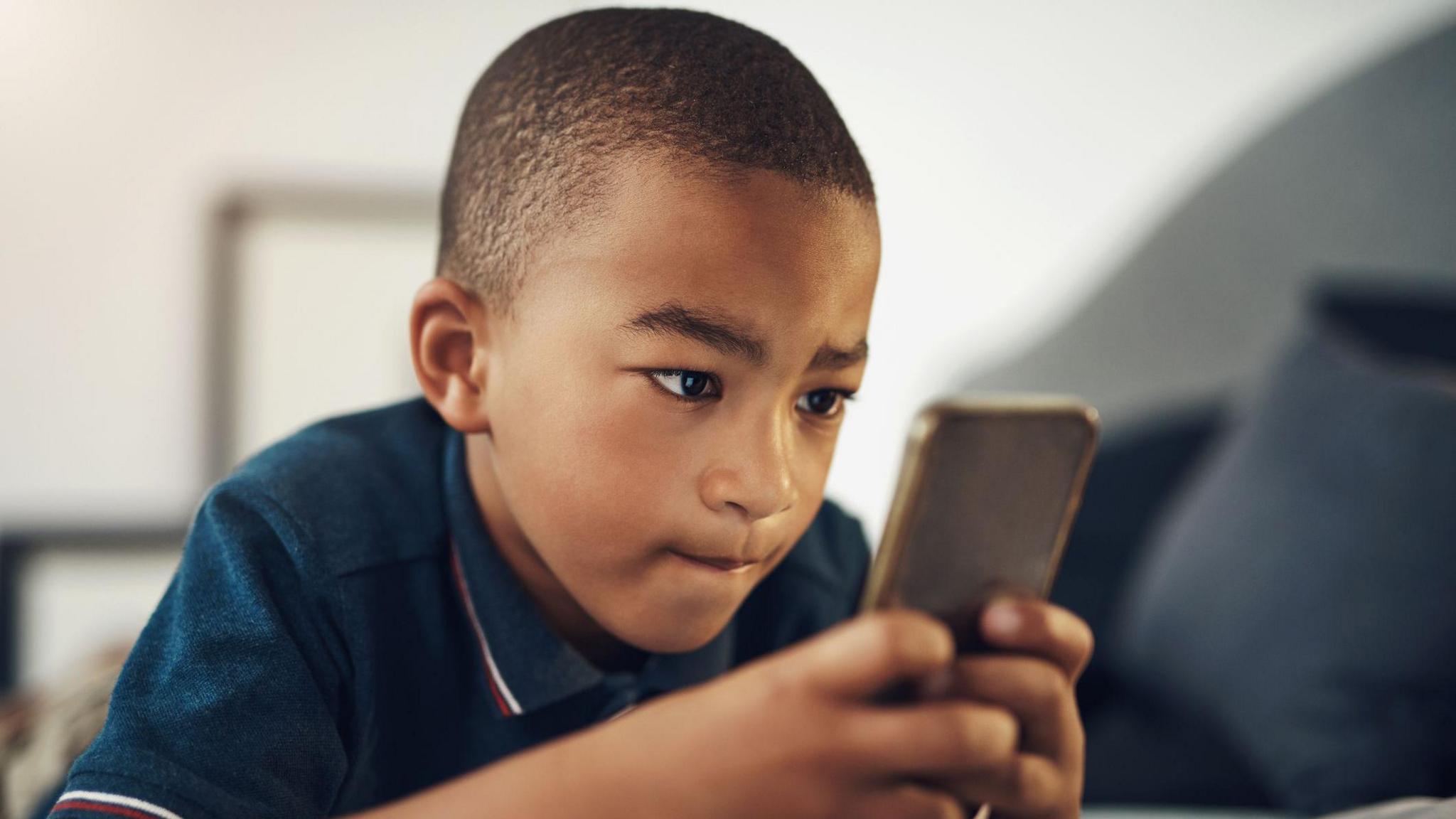 a young boy scrolling intently on a phone