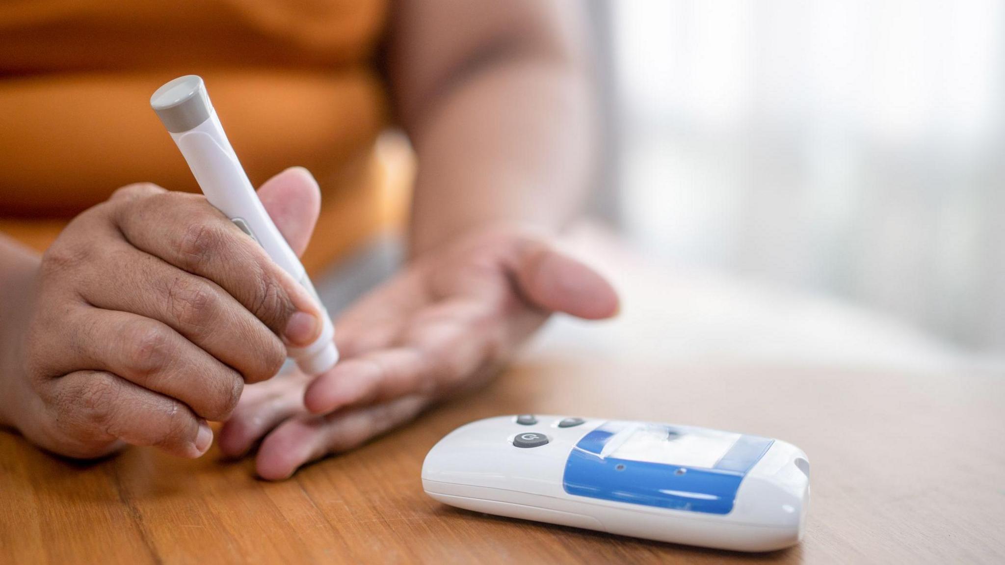 A person is testing their blood sugar with a finger prick test via a portable machine.