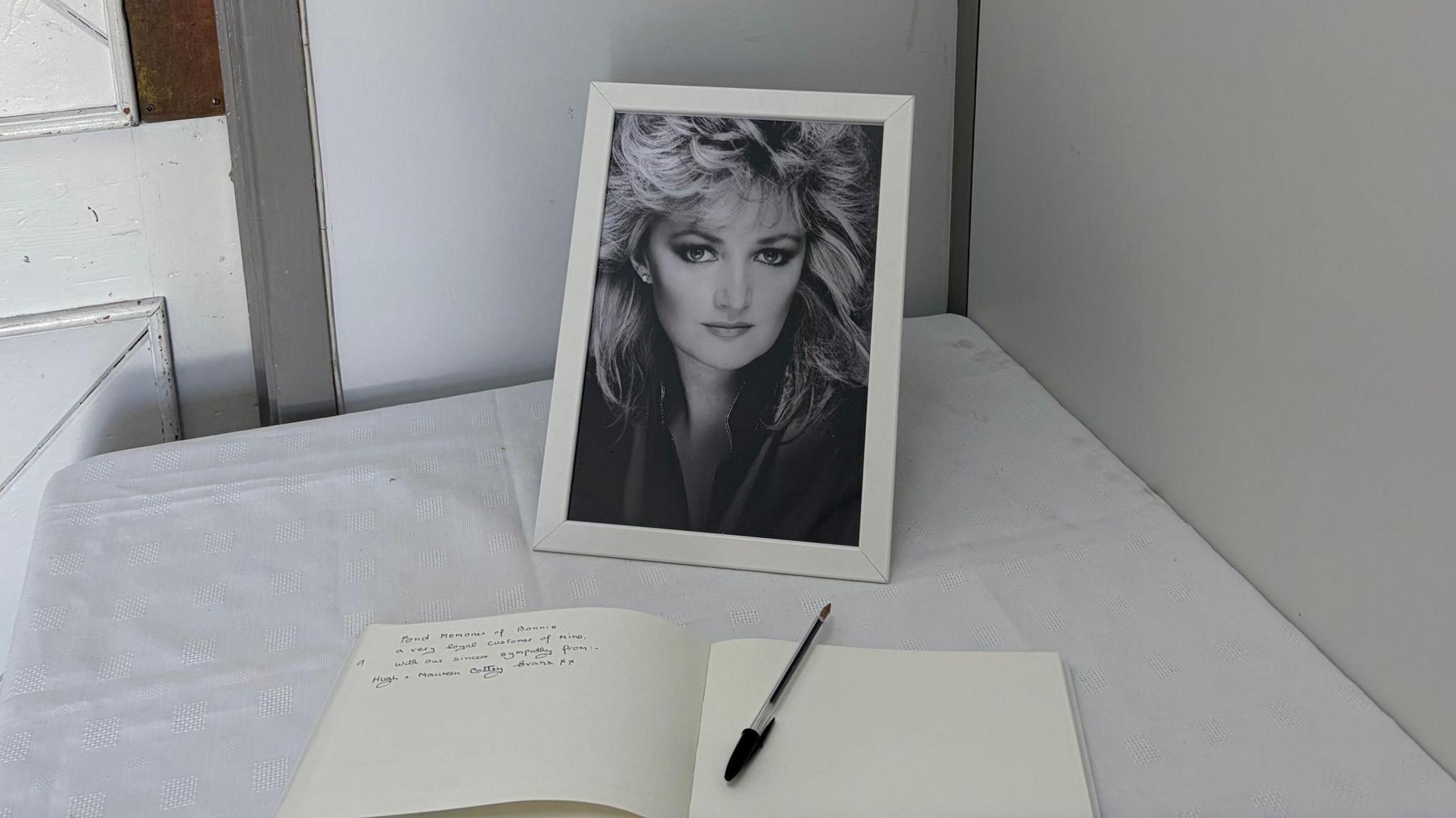 Llun o Bonnie Tyler mewn canolfan tu ôl i lyfr atgofion.