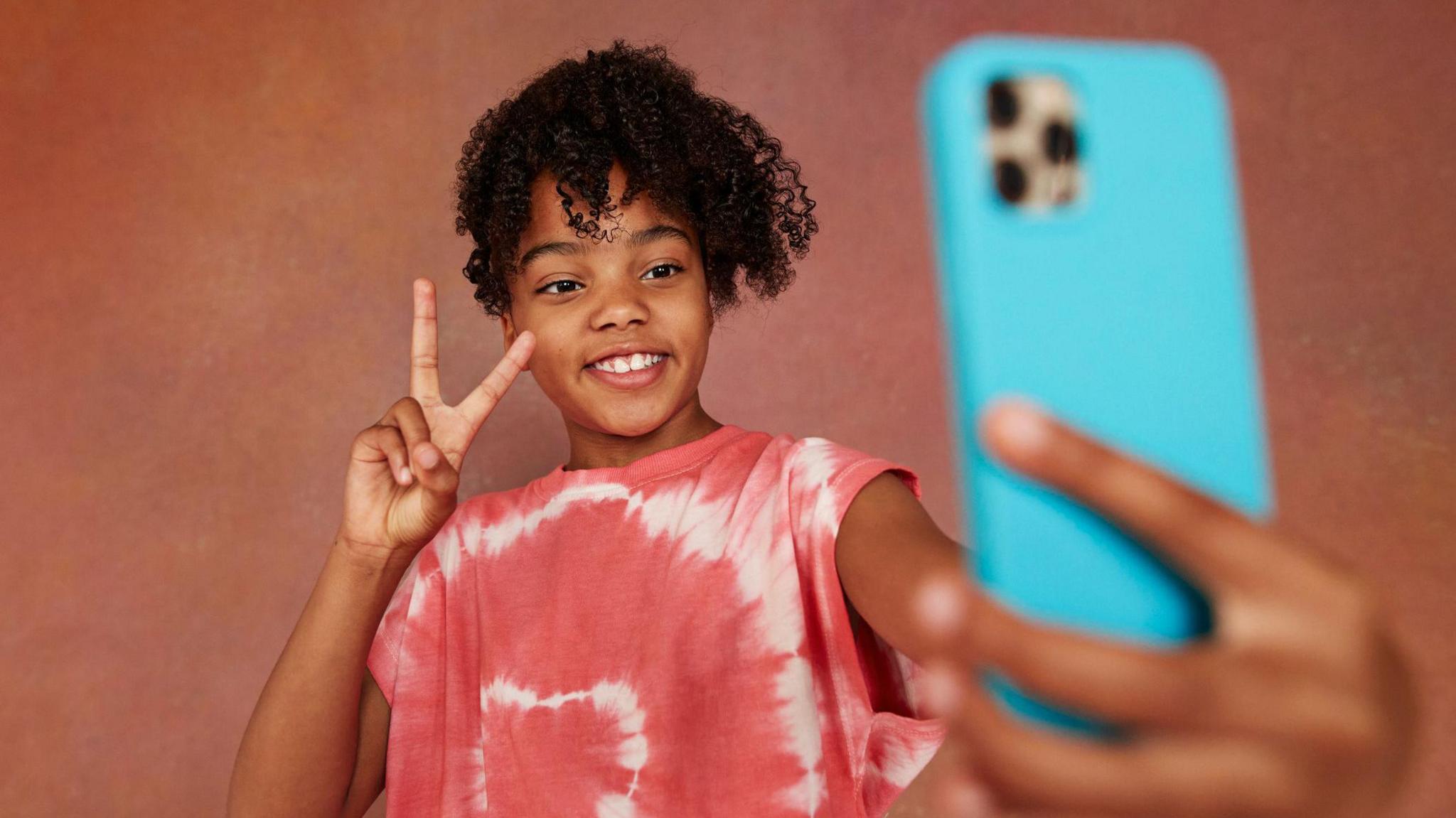 a girl holding out her phone and taking a selfie