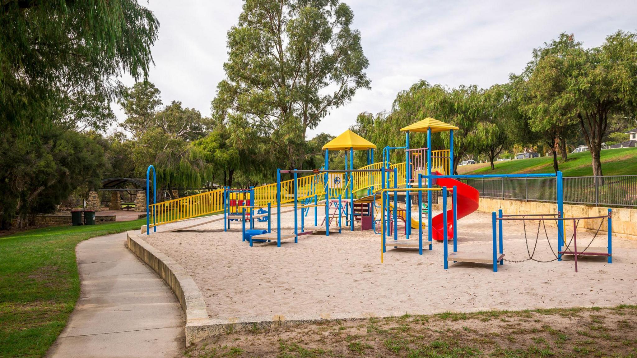 An empty playground surrounded by trees and grass.
