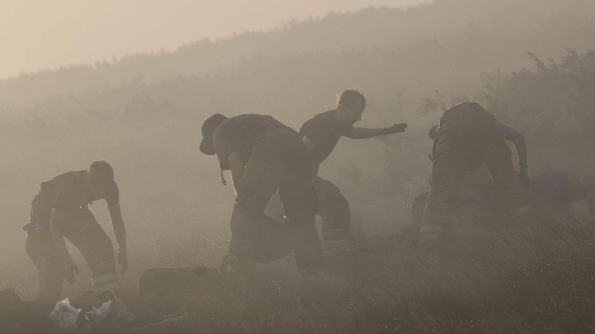 Firefighters viewed through a miasma of smoke