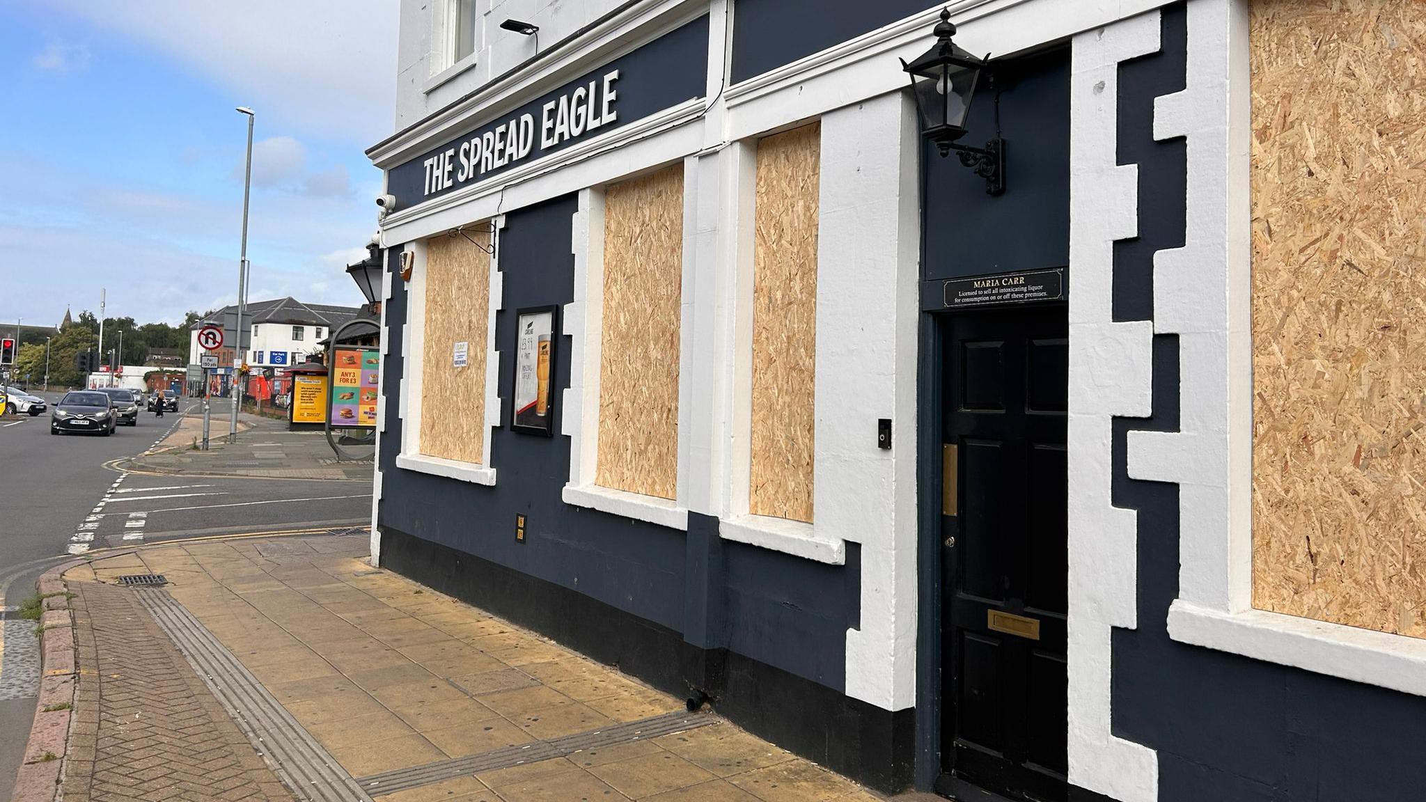 The side of a pub with boarded up windows