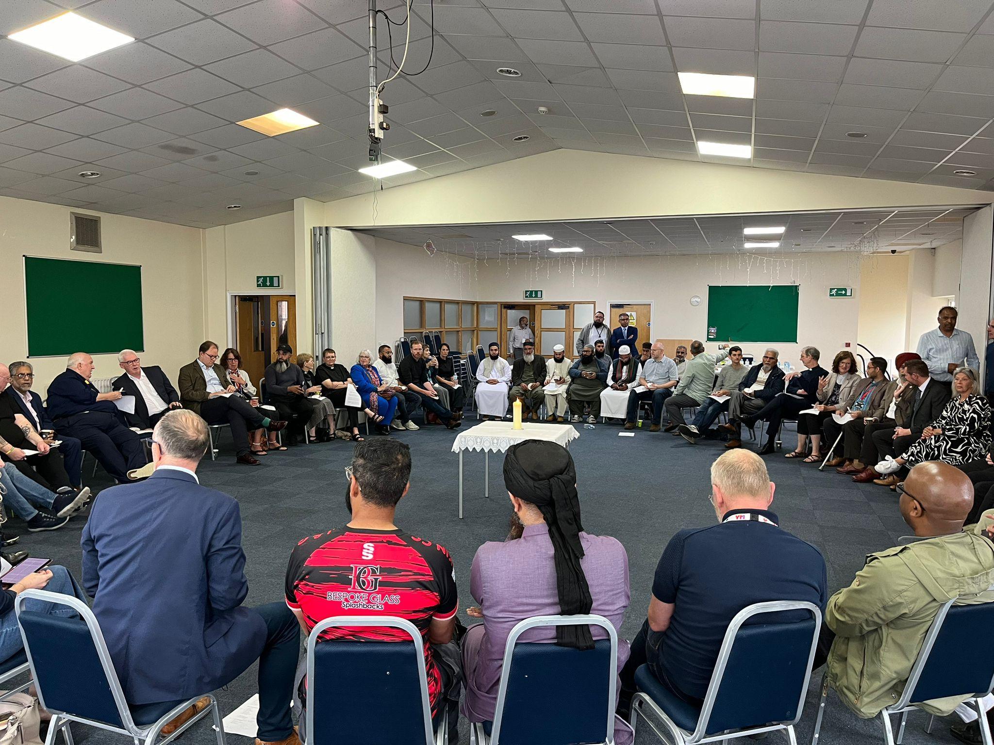 A group of around 50 people sit in a circle at an event in Hanley.