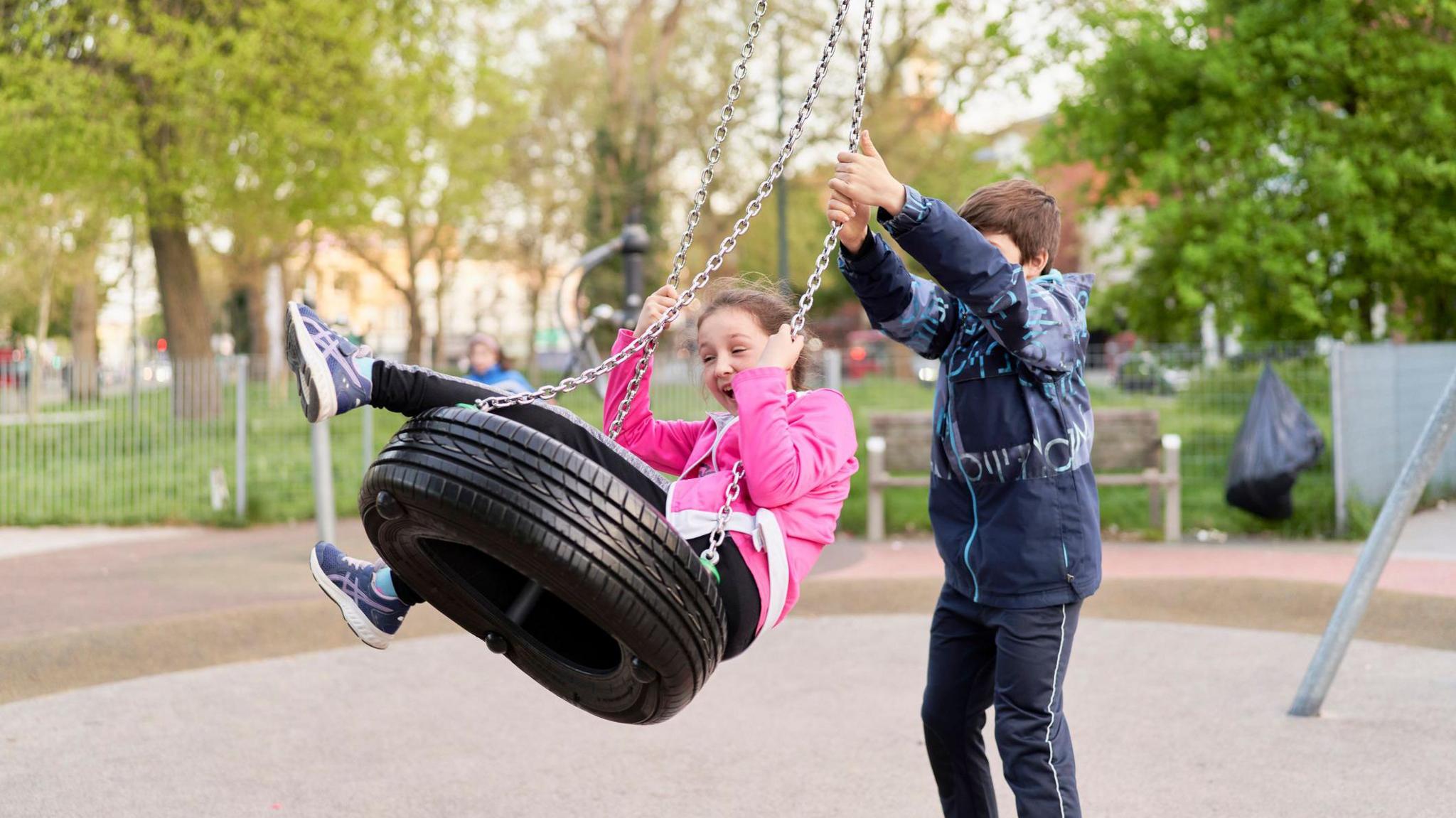 Children playing on a tyre swing in a playground